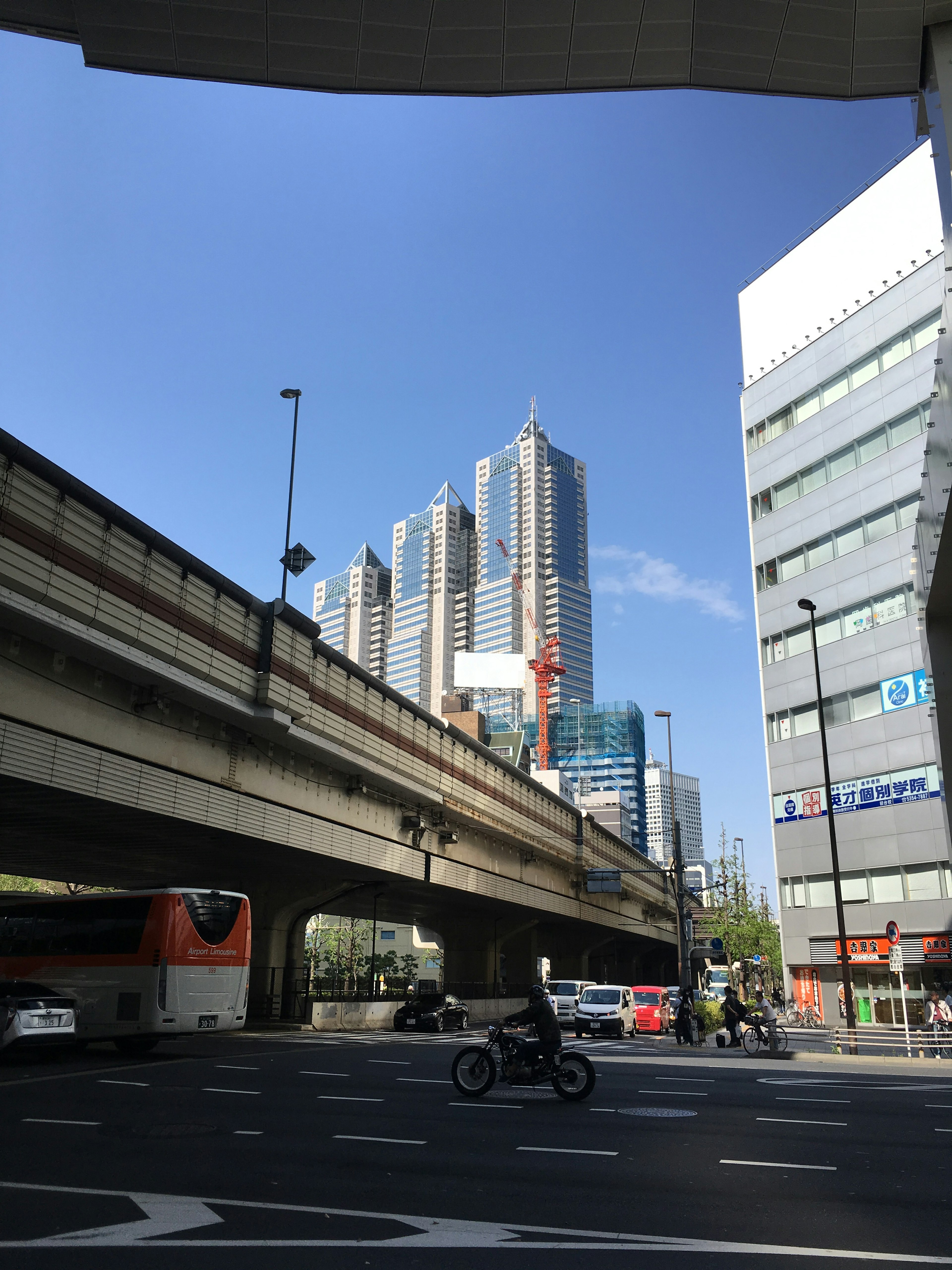 City skyline featuring tall buildings and blue sky viewed from under an overpass