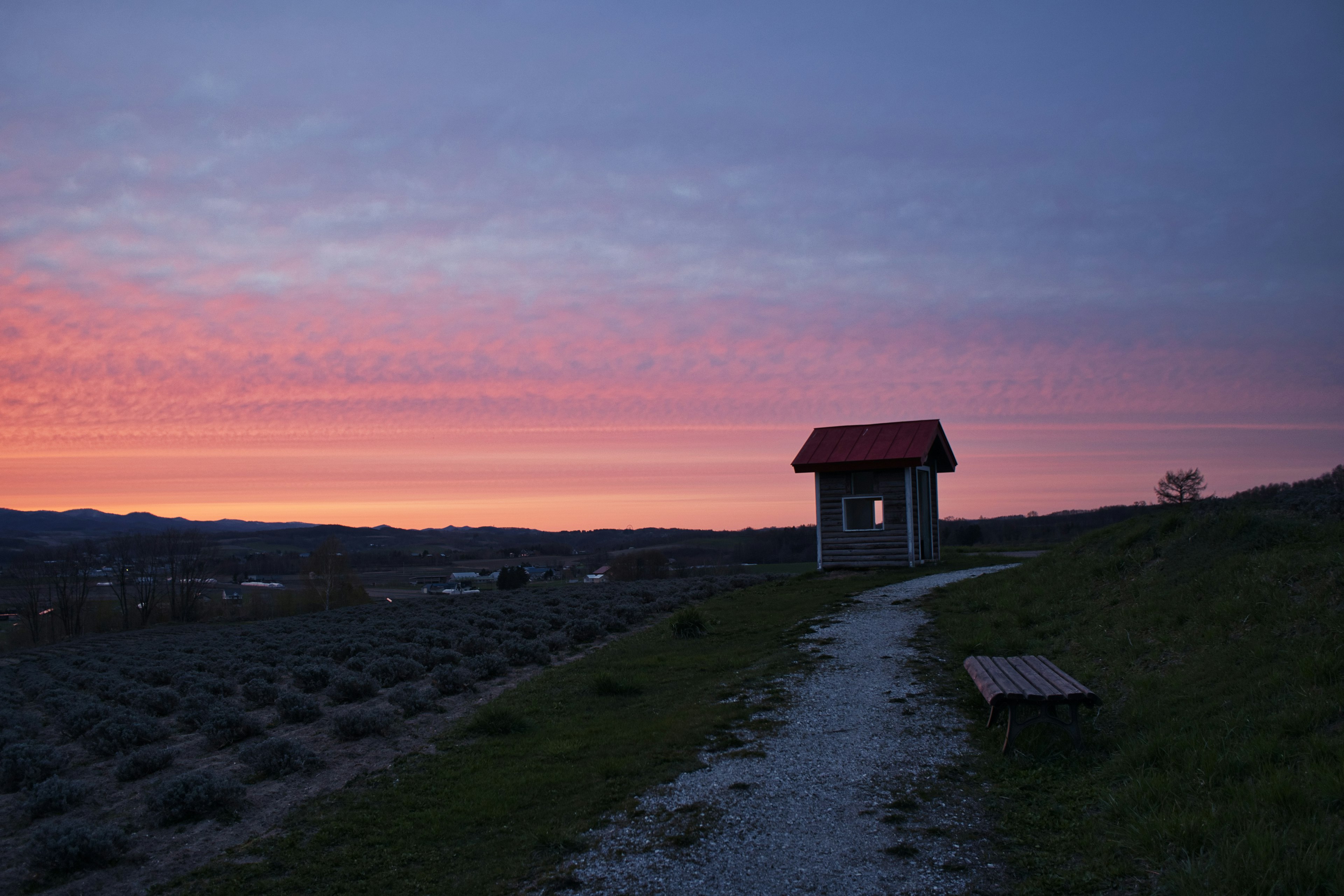 夕焼けに照らされた小屋と小道が見える風景