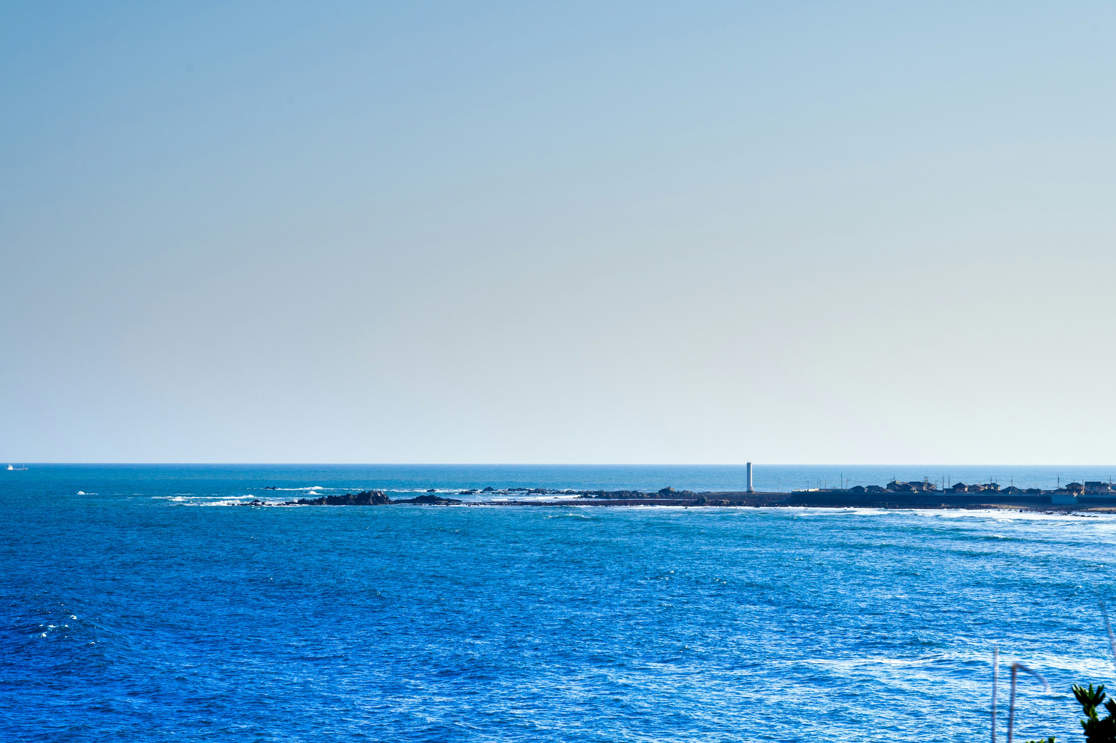 青い海と空が広がる景色に小さなボートが見える