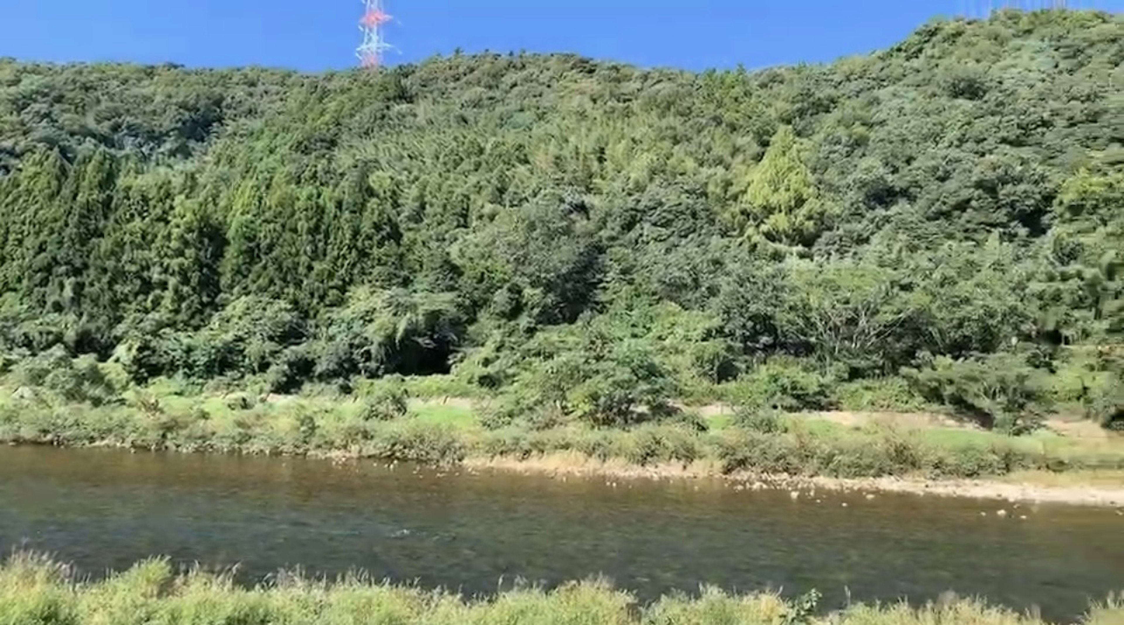 Pemandangan indah pegunungan hijau dan sungai di bawah langit biru