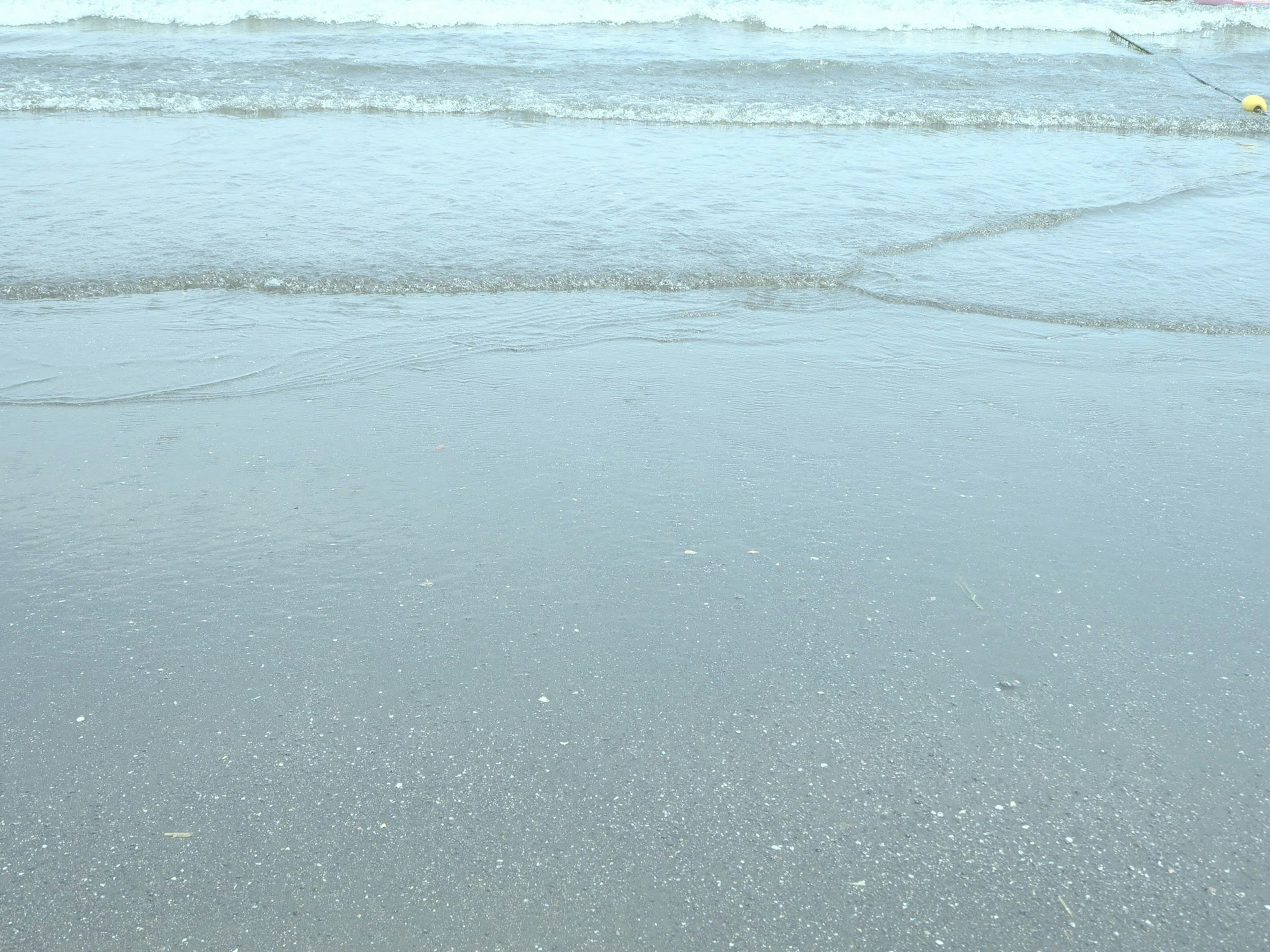 Sanfte Wellen des Ozeans, die an einen Sandstrand schlagen