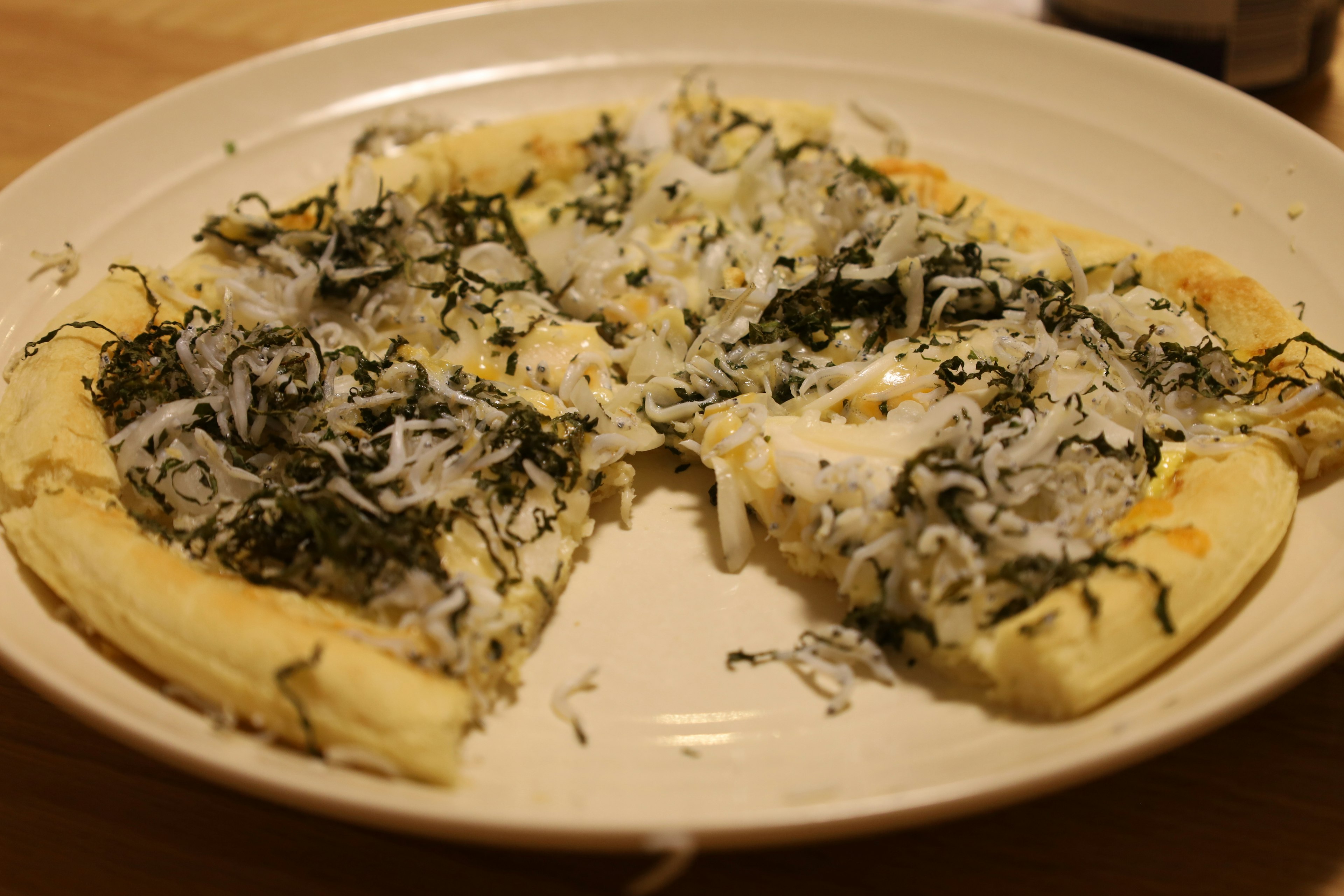 Japanese-style pizza topped with seaweed and cheese on a plate