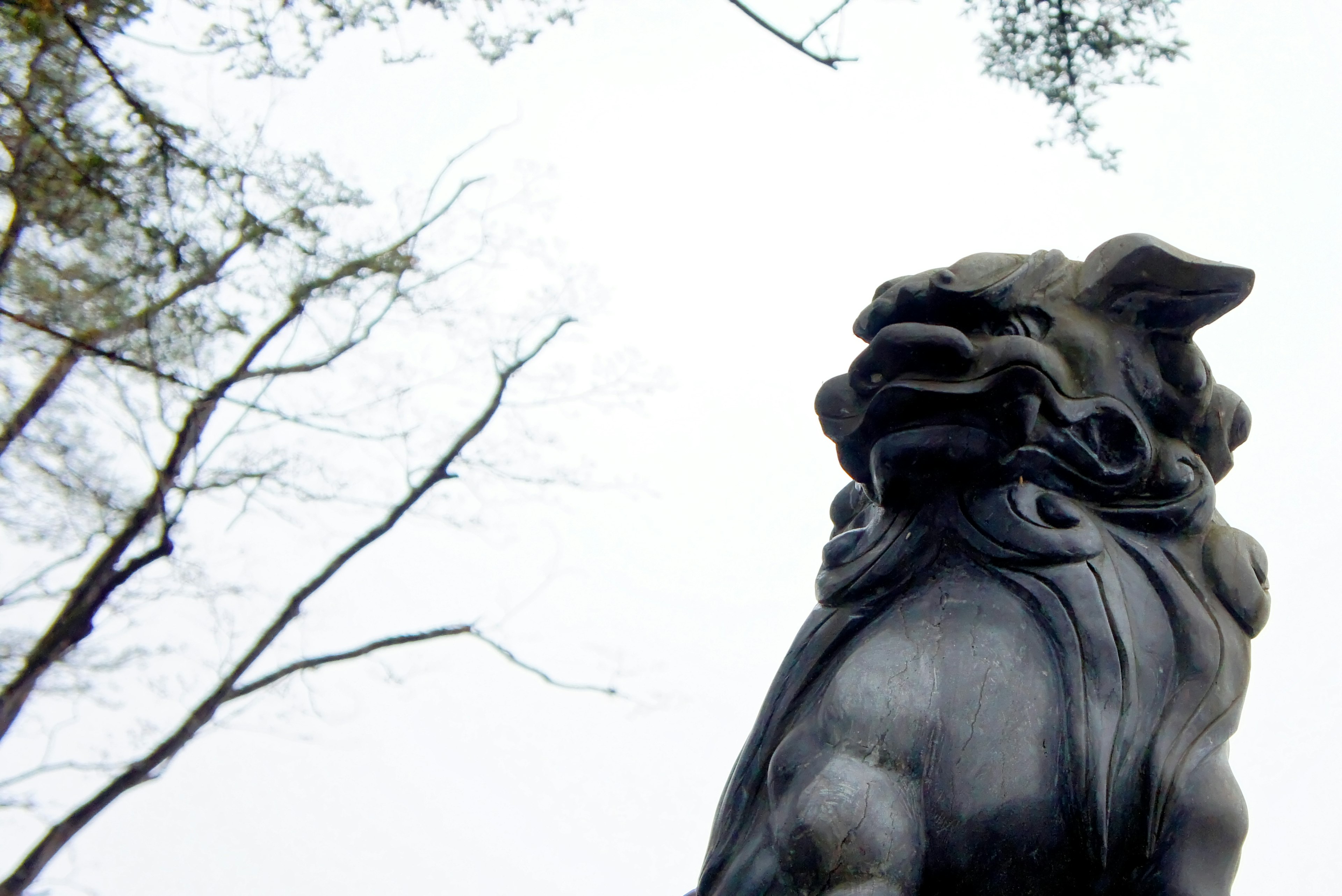 Black lion sculpture stands against a backdrop of trees