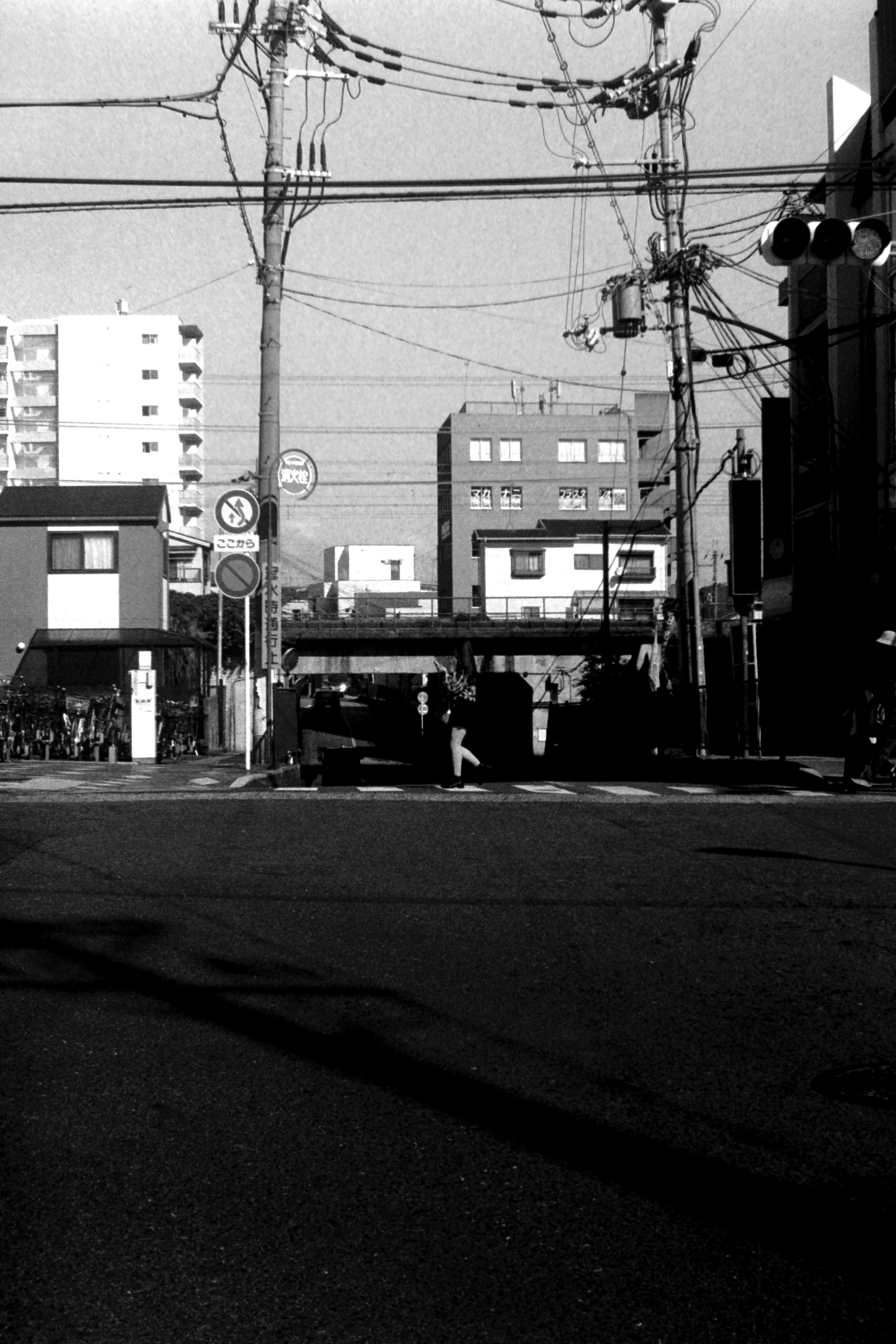 Escena urbana en blanco y negro intersección con líneas eléctricas edificios y siluetas de personas