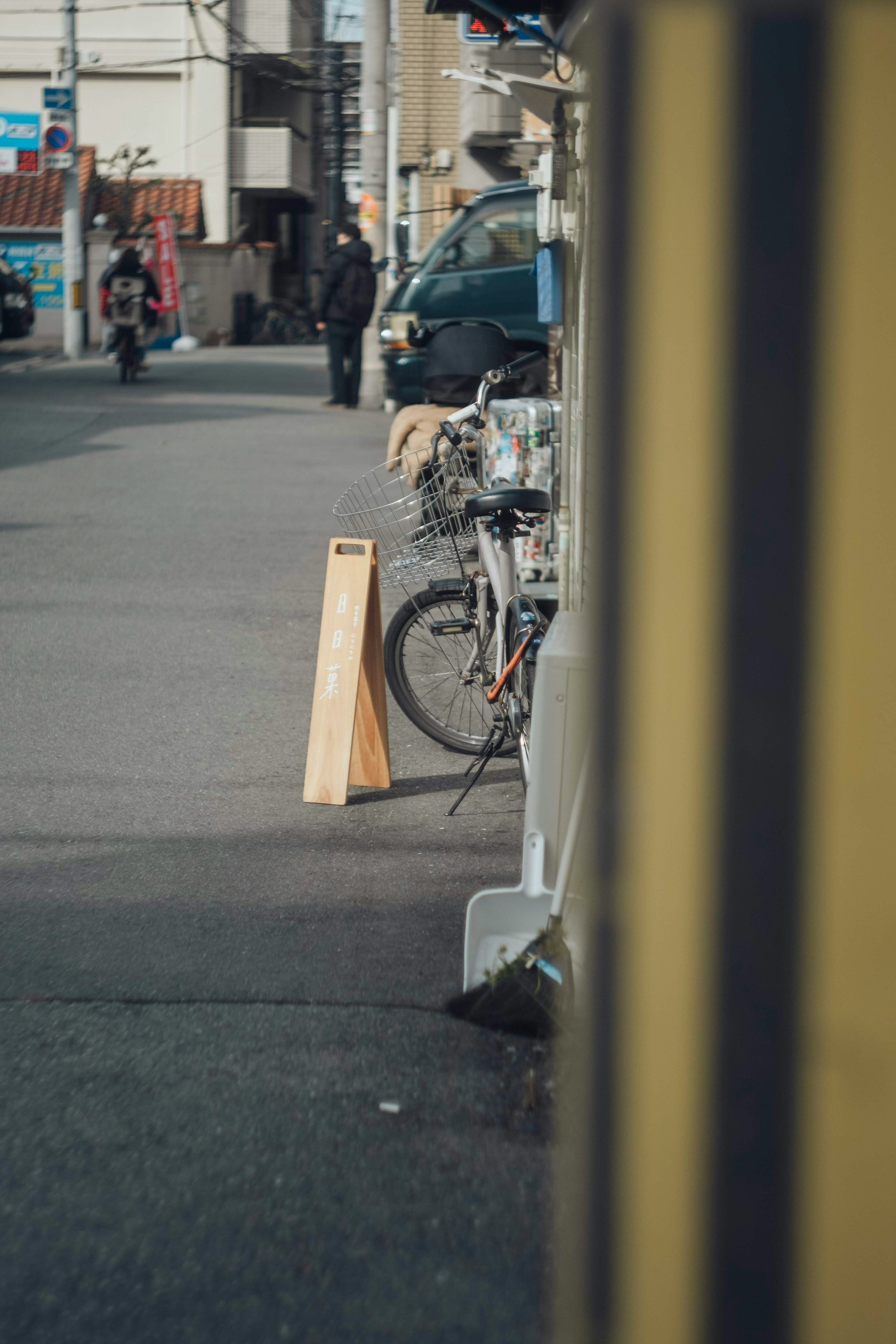 Scène de rue avec un vélo et un panneau en bois