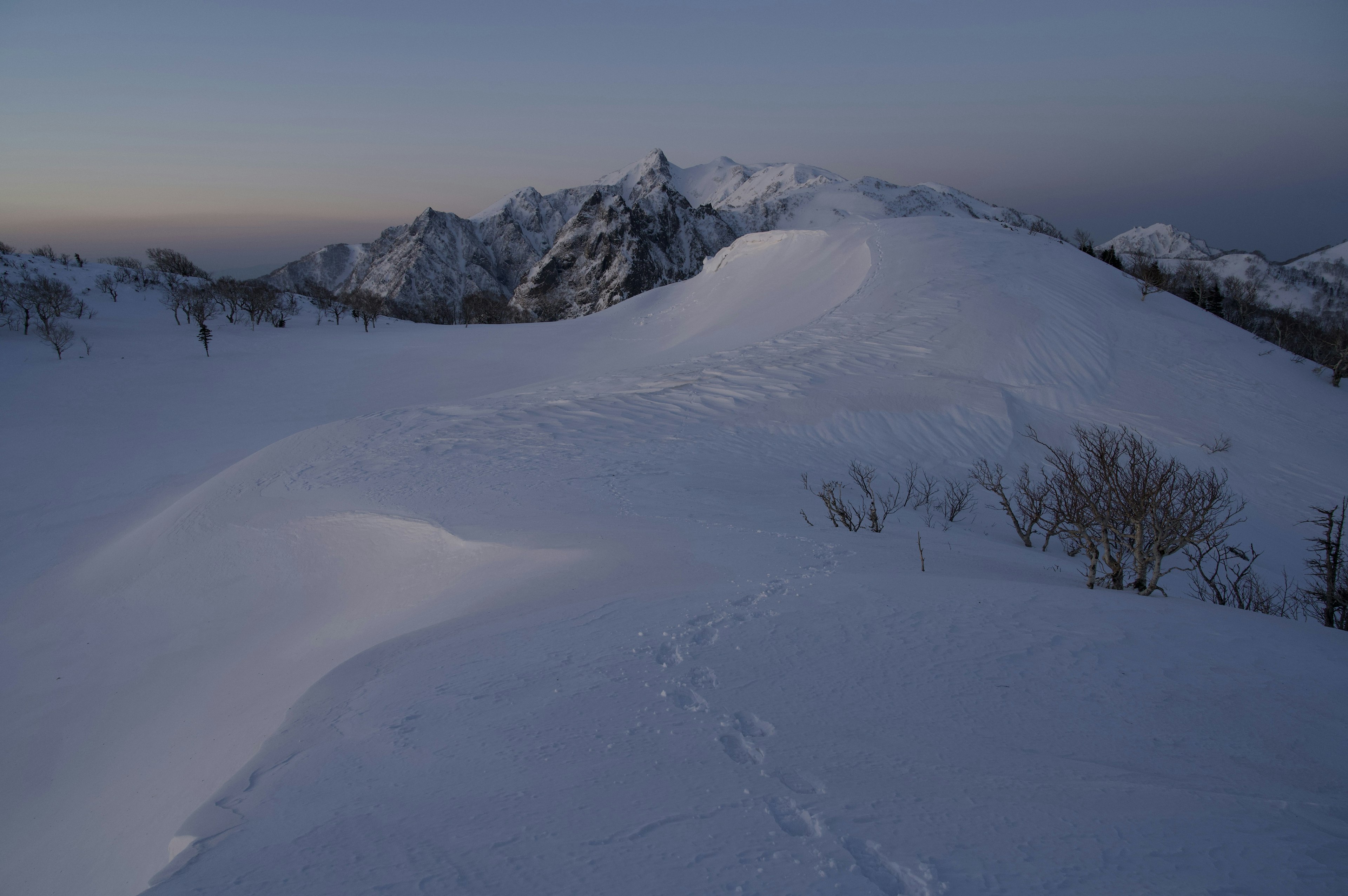 雪に覆われた山の風景と薄明かりの空