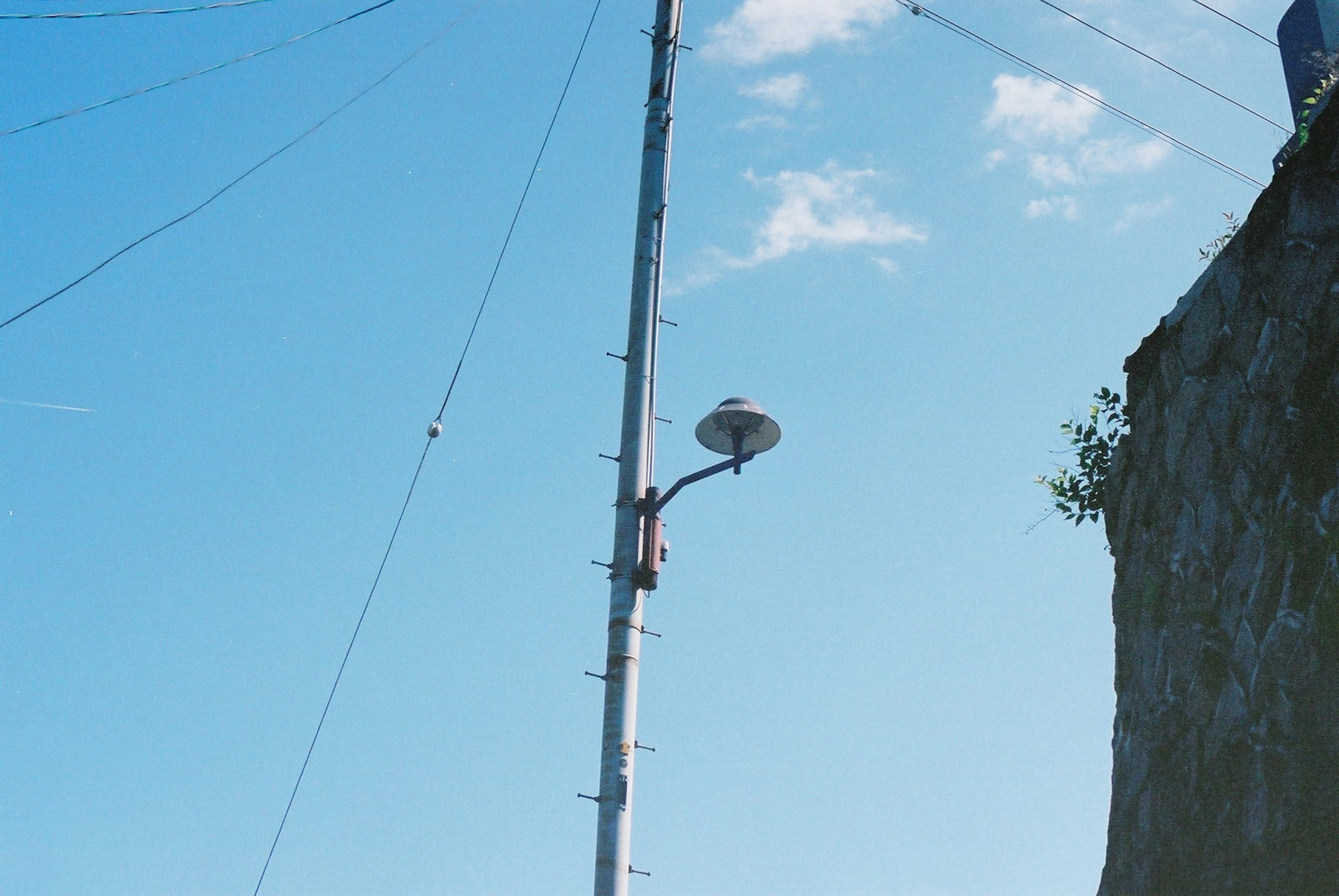 Imagen de una farola en un poste alto bajo un cielo azul