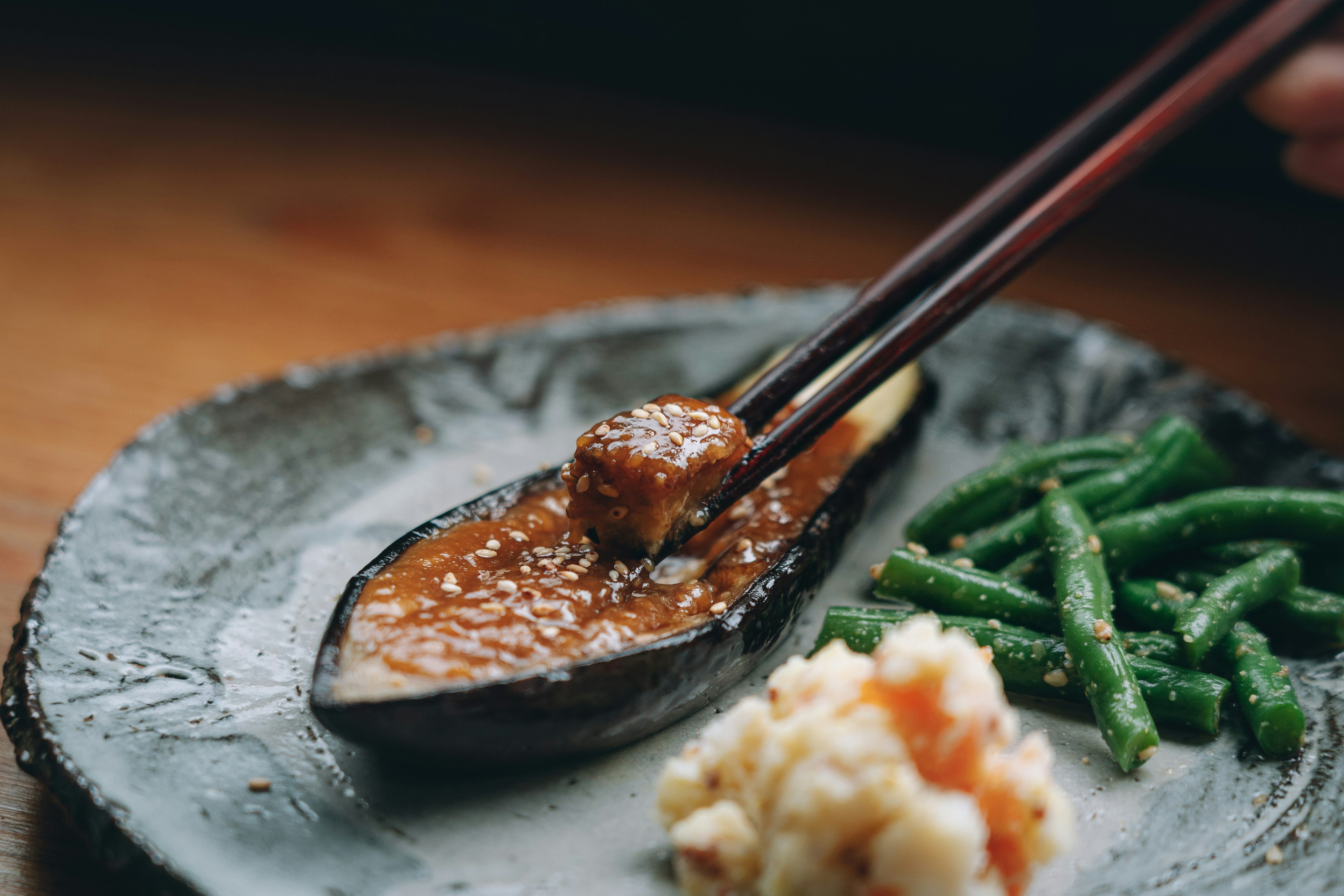 A dish featuring a meatball in sauce served on a plate with green beans and a creamy side