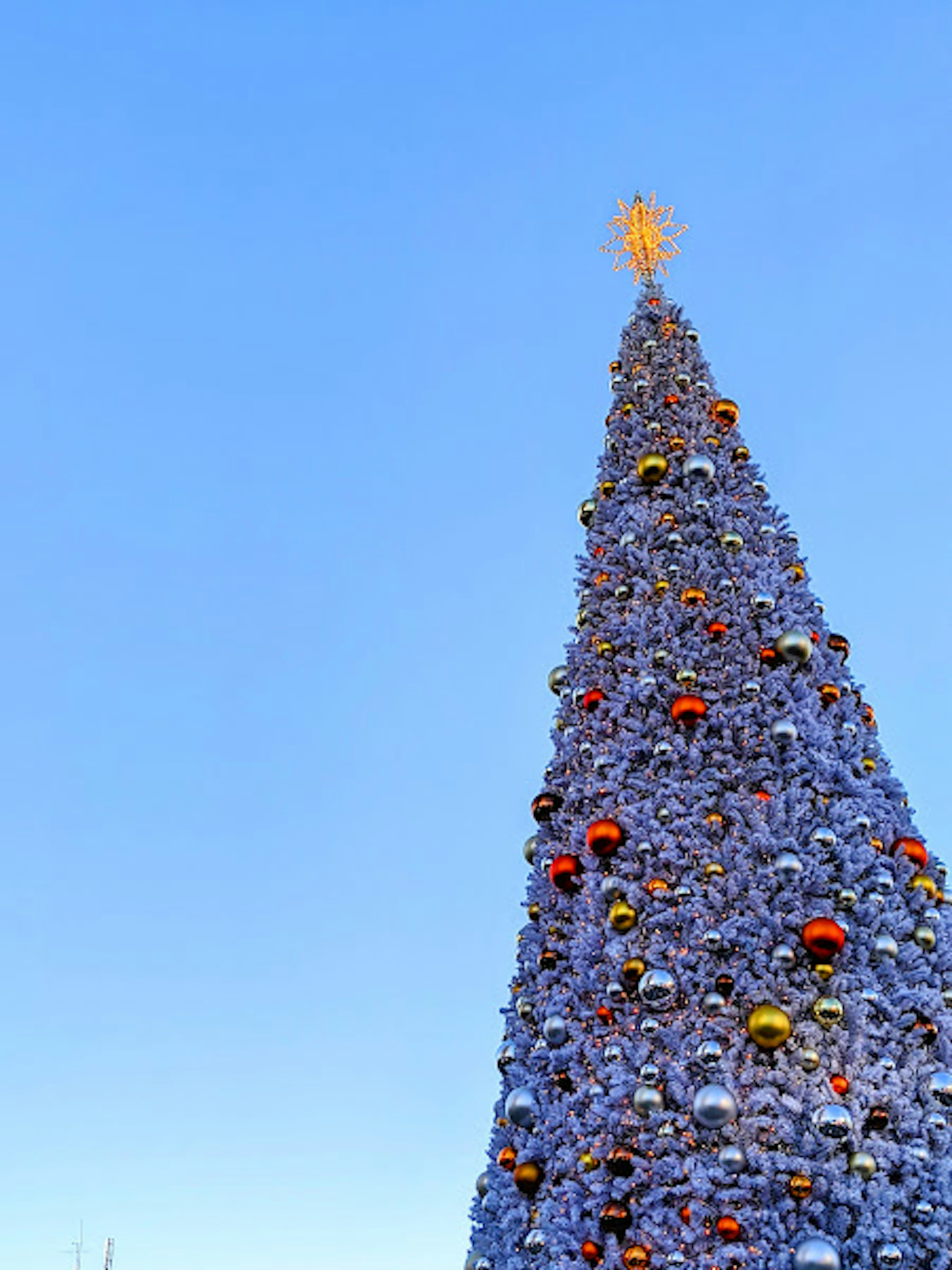 Árbol de Navidad decorado bajo un cielo azul