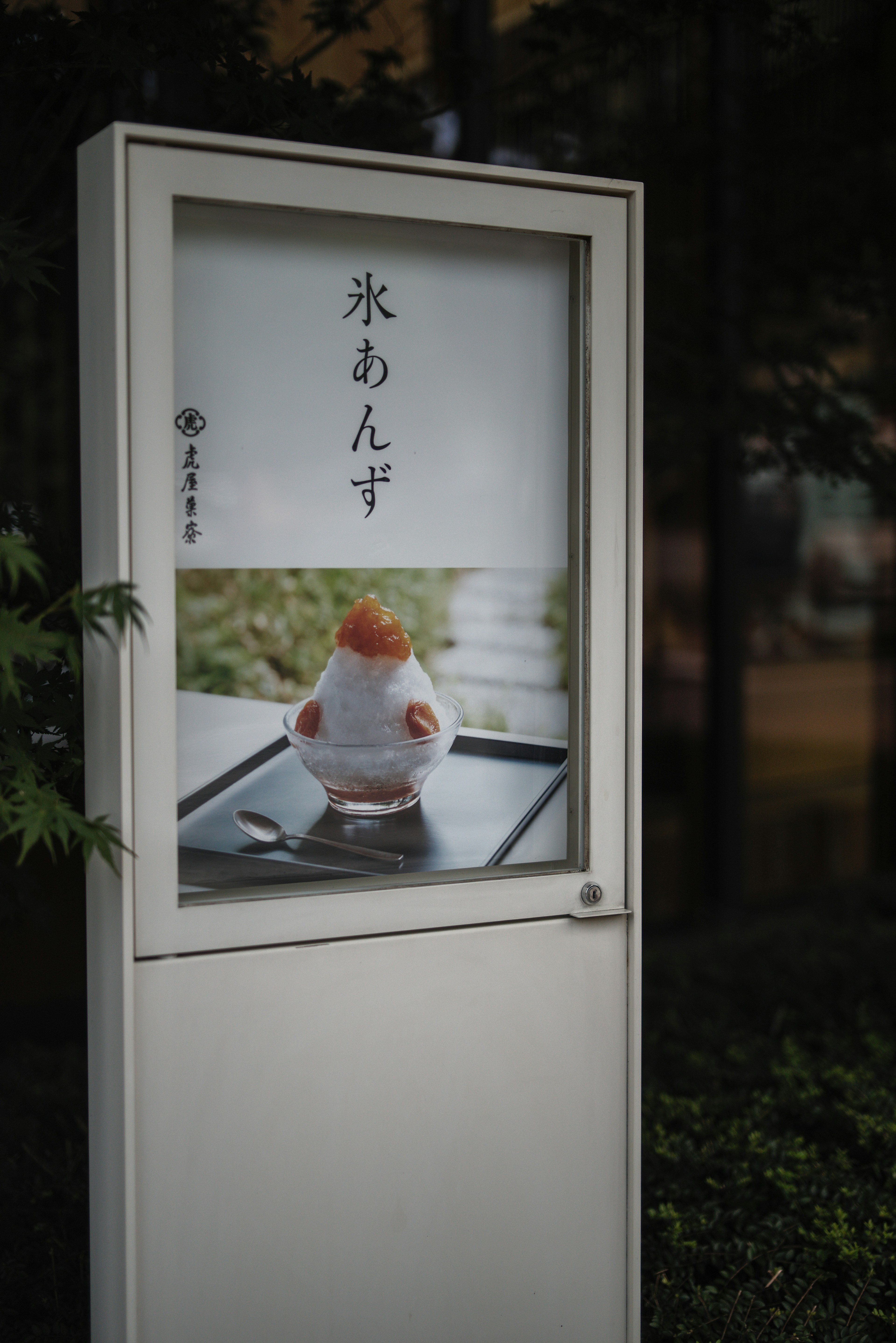 白い看板に氷あんみつの写真があり、緑の背景が特徴的