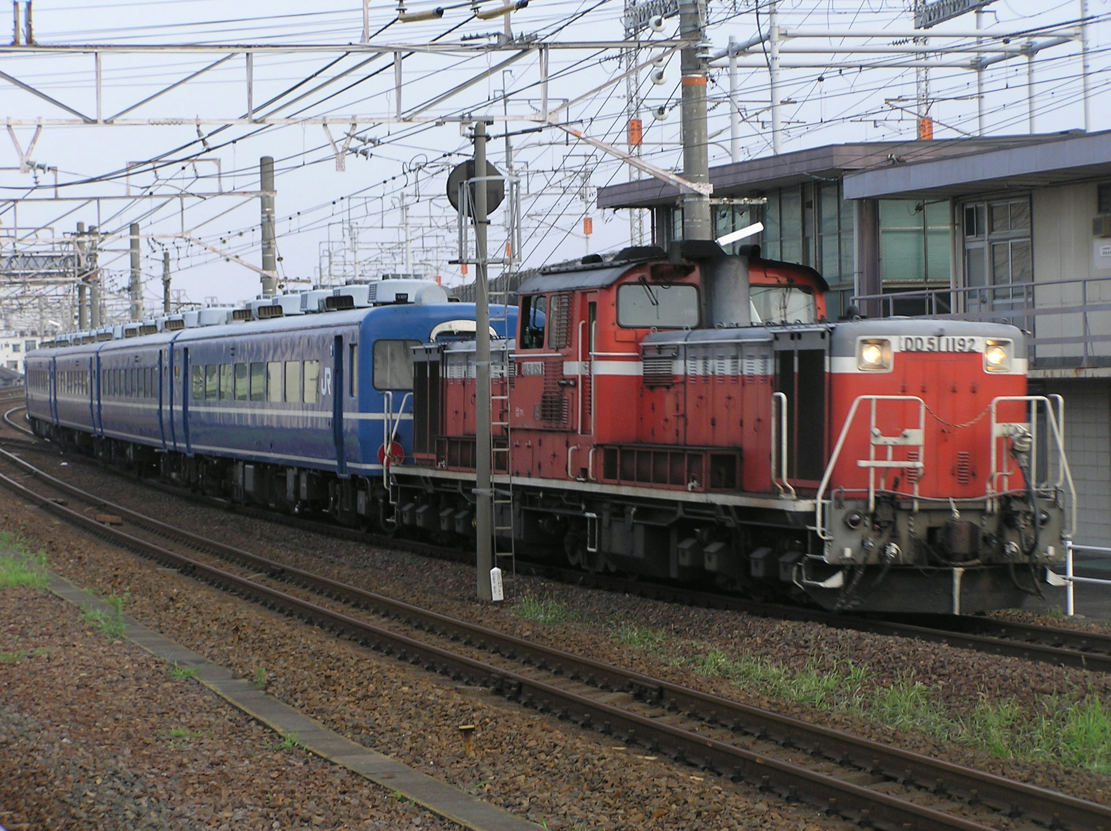 Locomotora roja pasando un tren azul en una curva