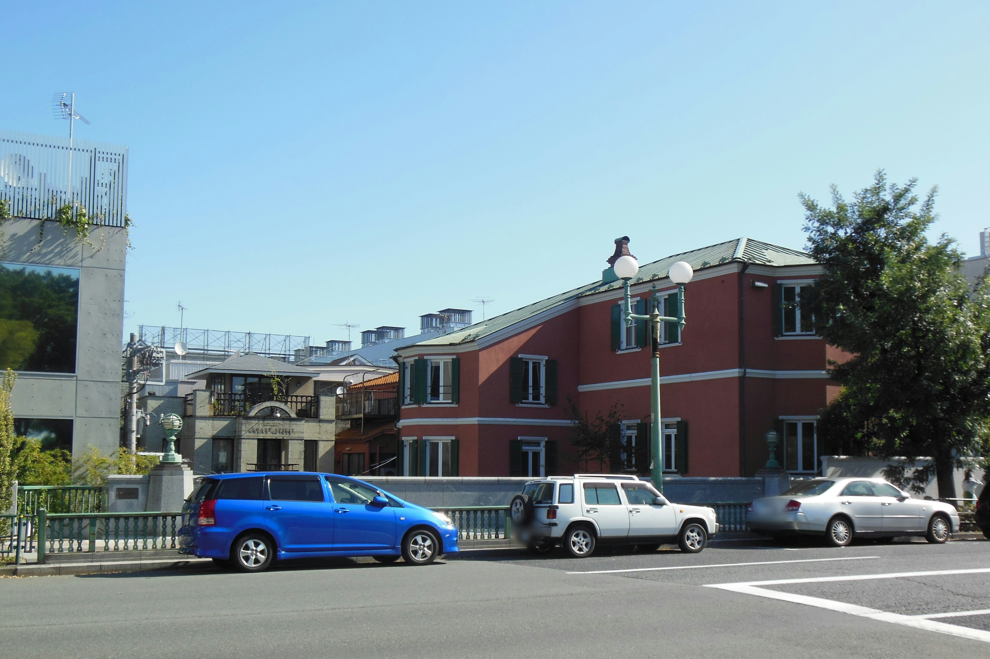 Vista di strada con un edificio in mattoni rossi e un'auto blu parcheggiata