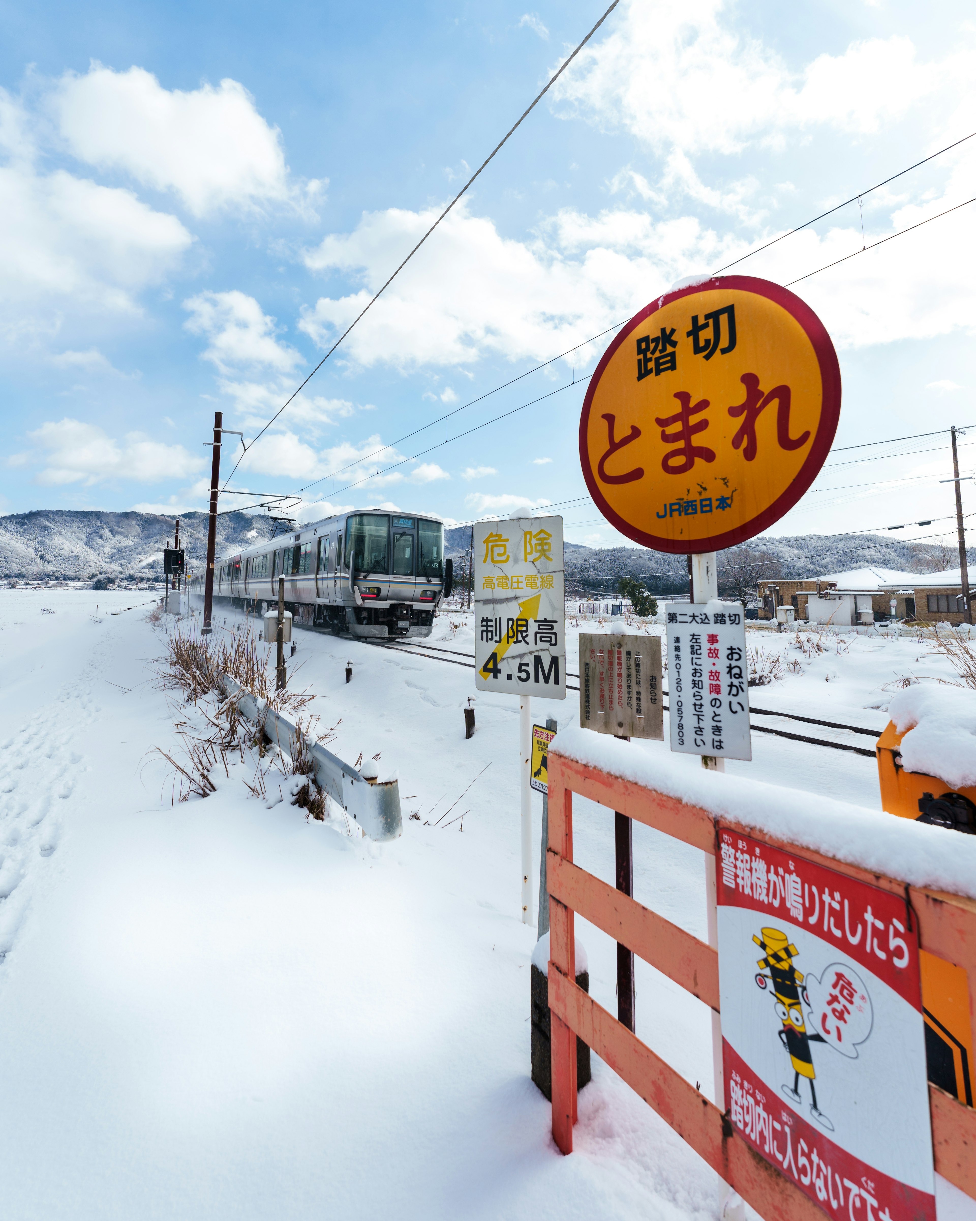 雪に覆われた鉄道駅の風景 駅名はとまれ 鉄道が背景に見える