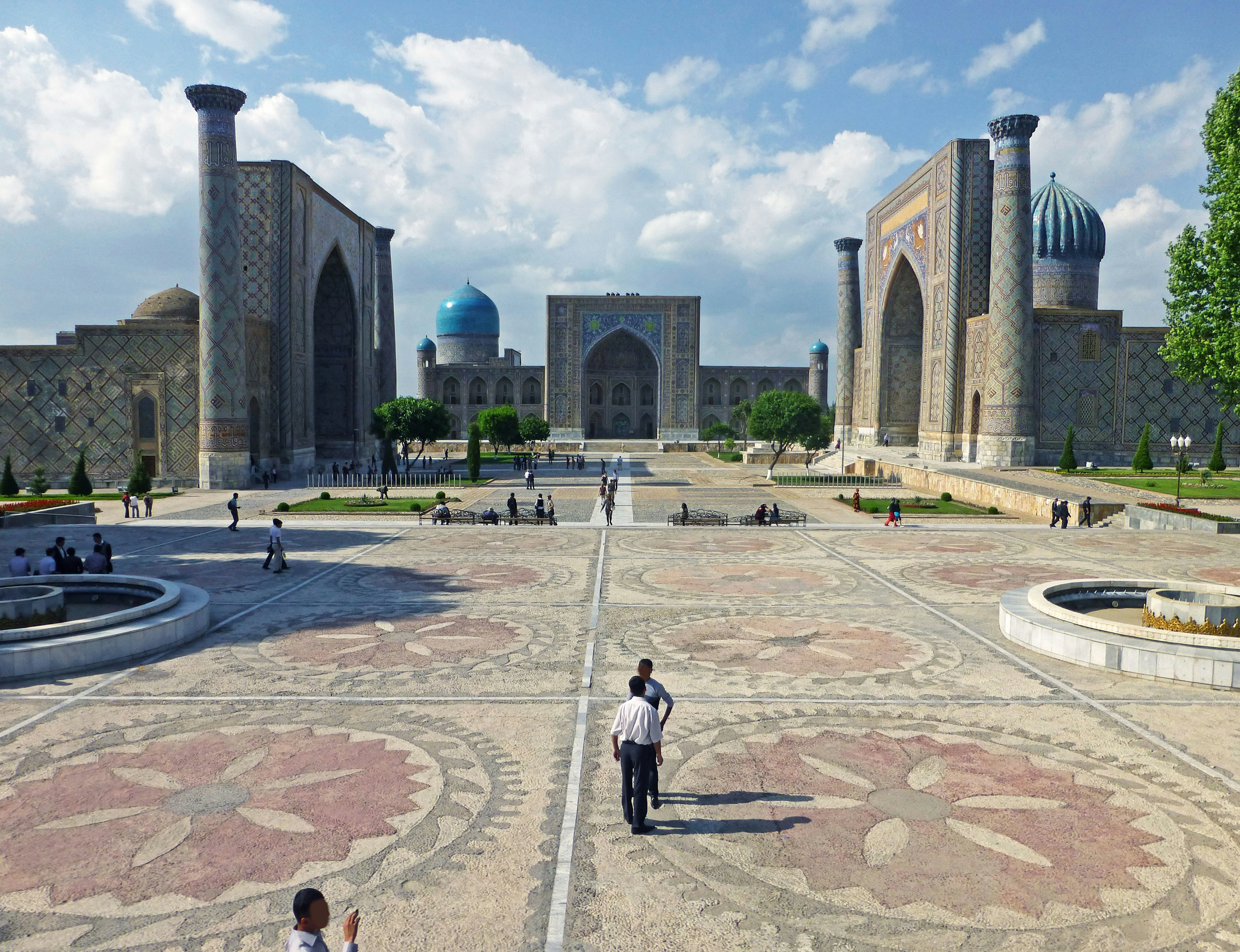 A view of Samarkand's square featuring historical buildings and people walking