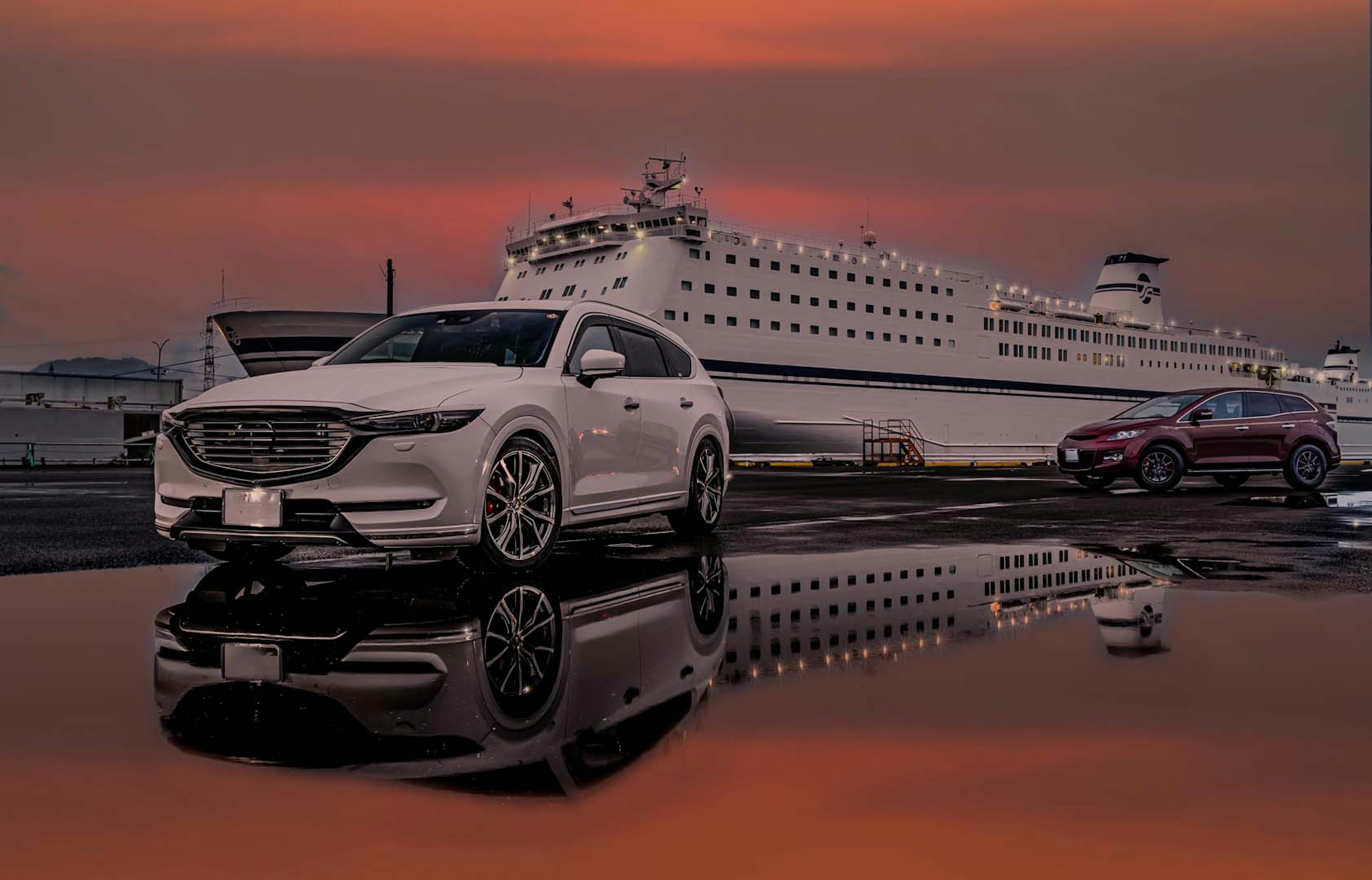 White SUV parked by a large ferry with a sunset reflection