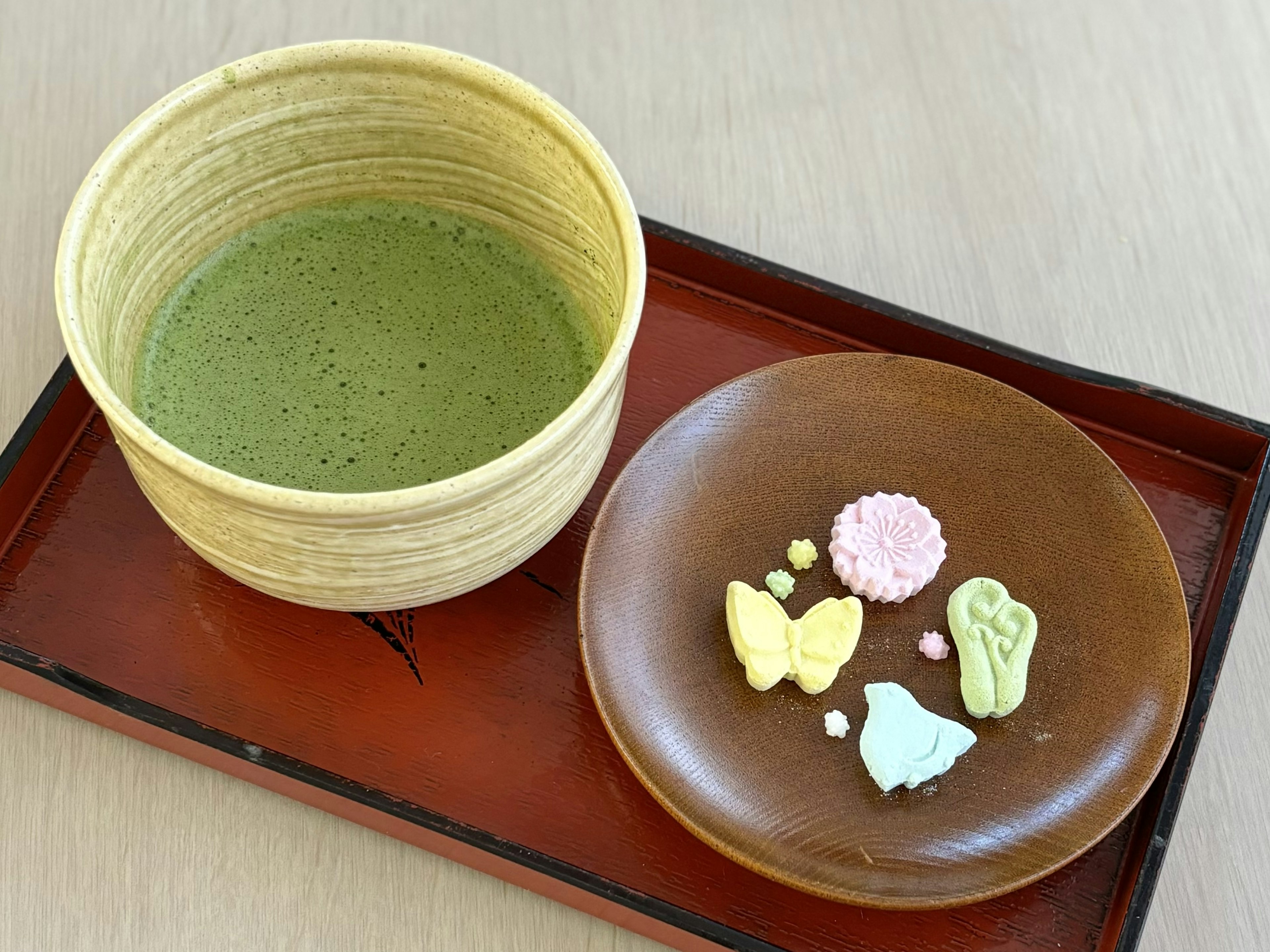 Tè matcha servito con dolci giapponesi colorati su un vassoio