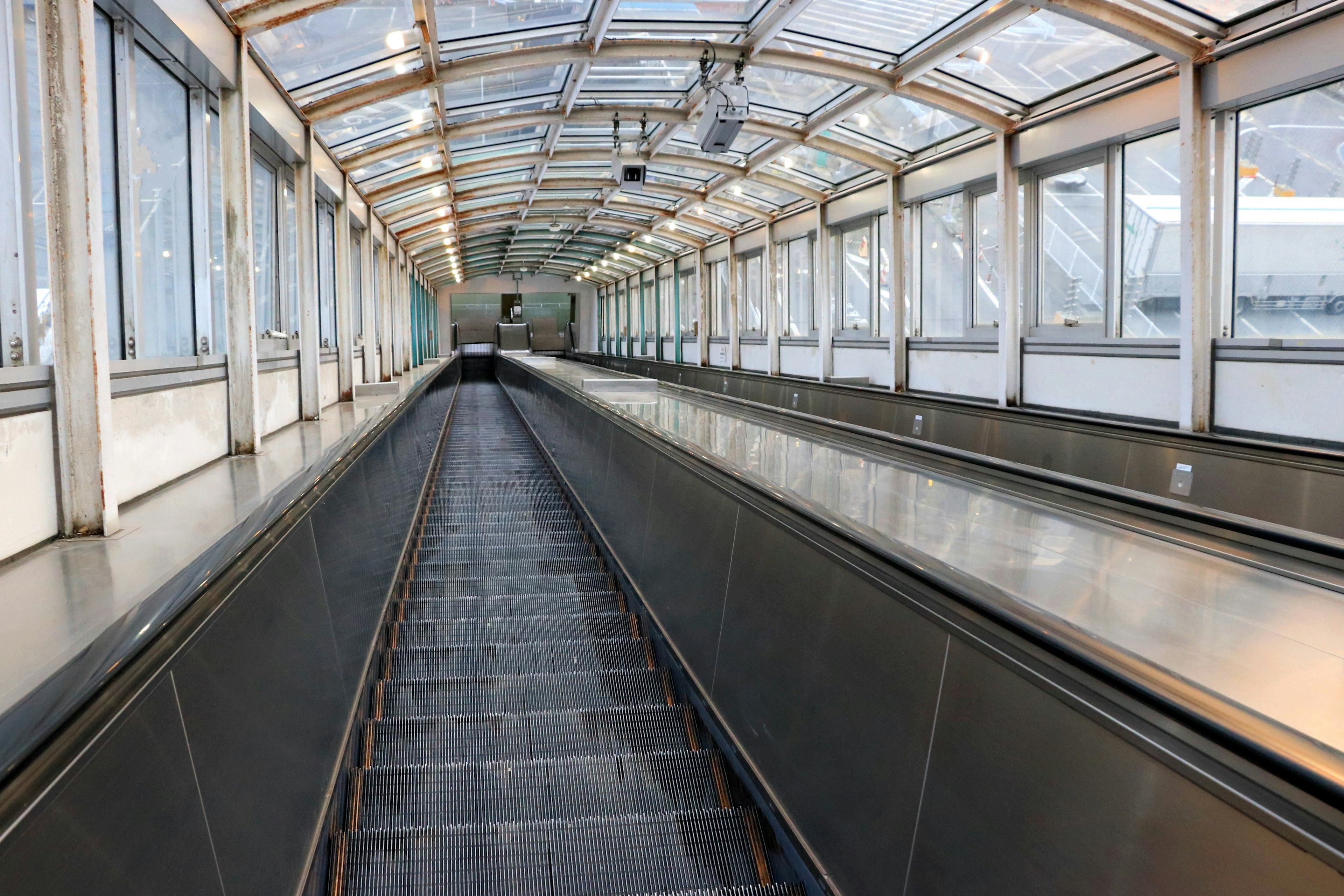 Interior of a covered escalator walkway with glass roof