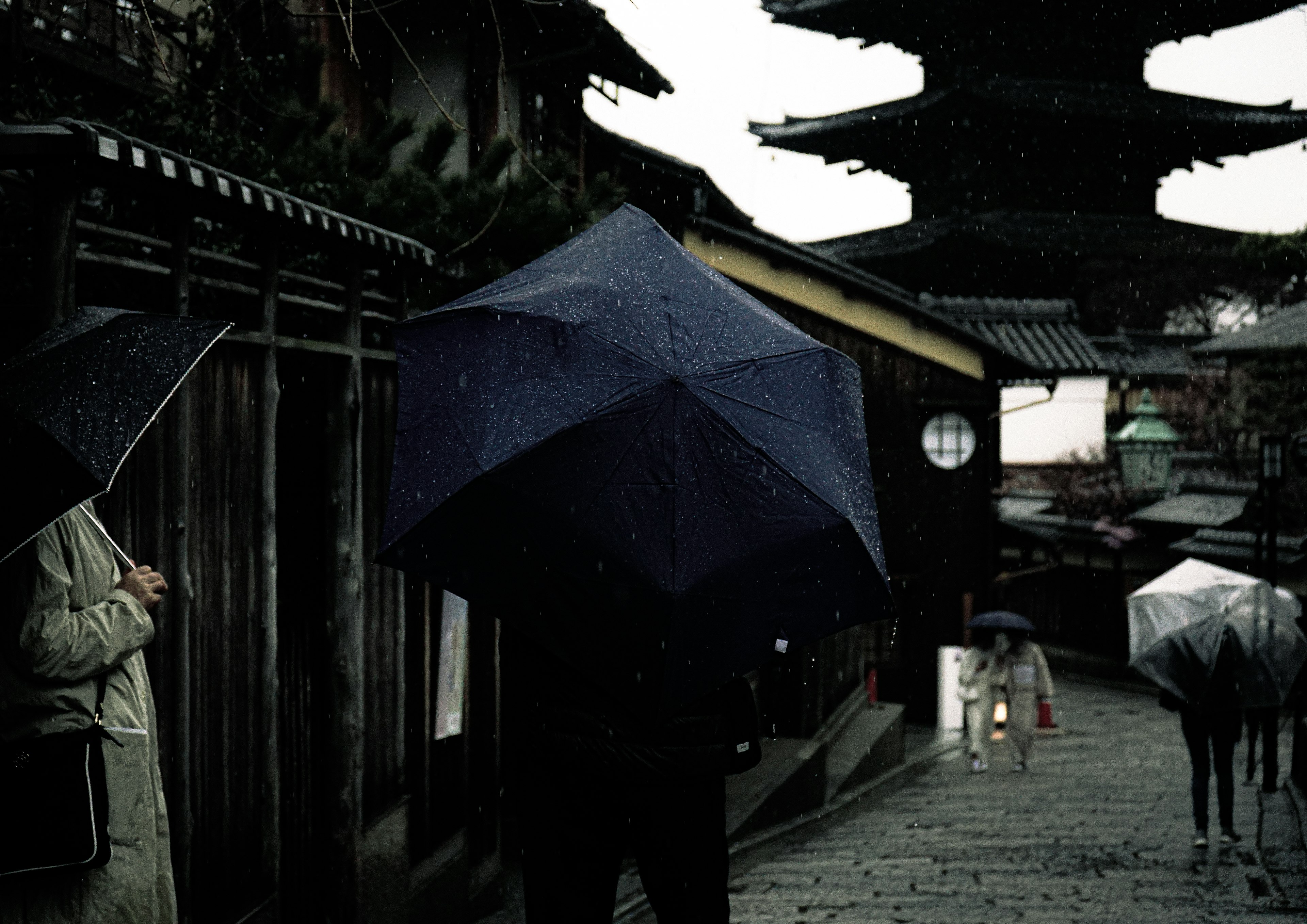 雨の中の古い街並みと傘を持つ人々