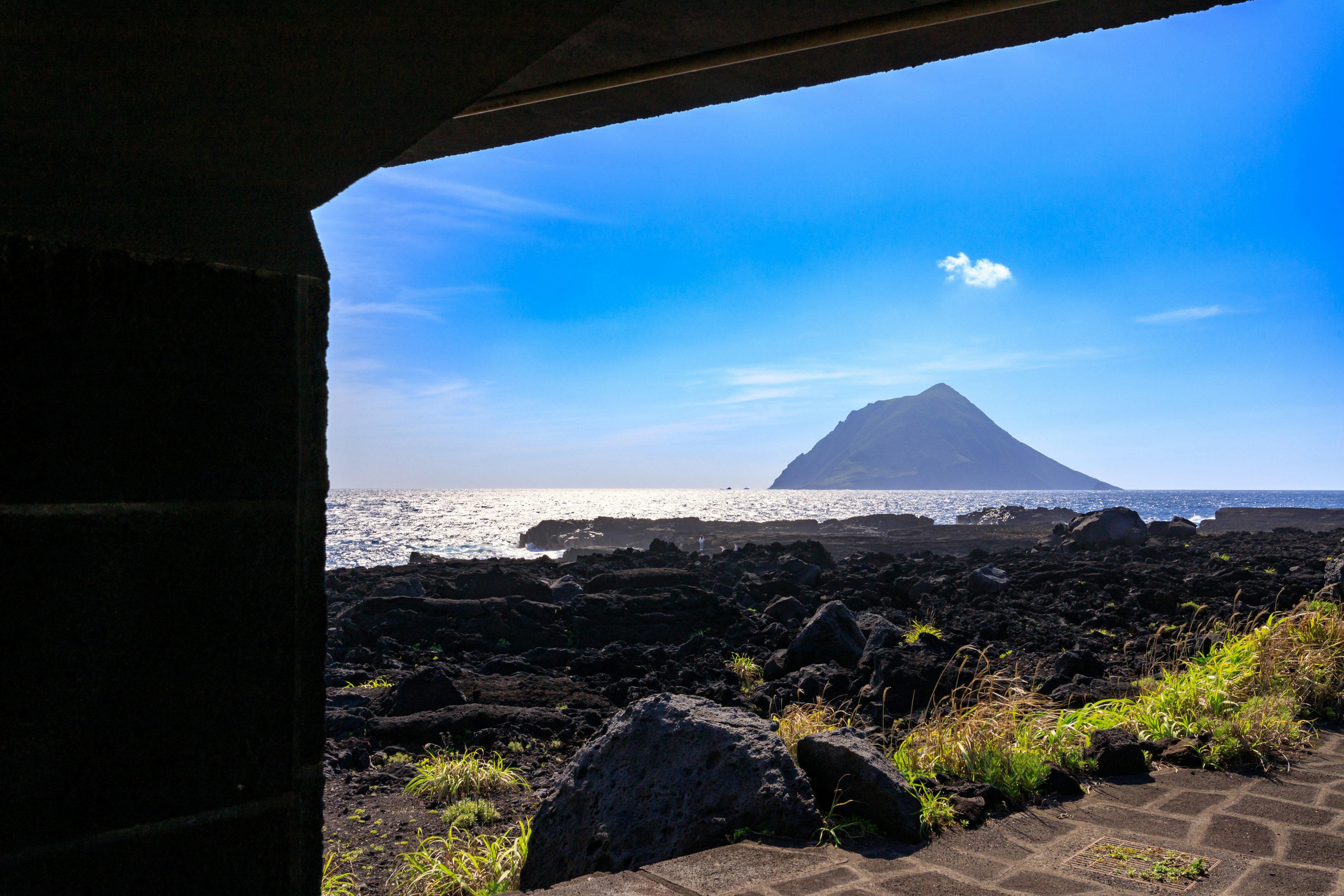 青い空と海の景色を背景にした岩の島が見える窓の外の風景