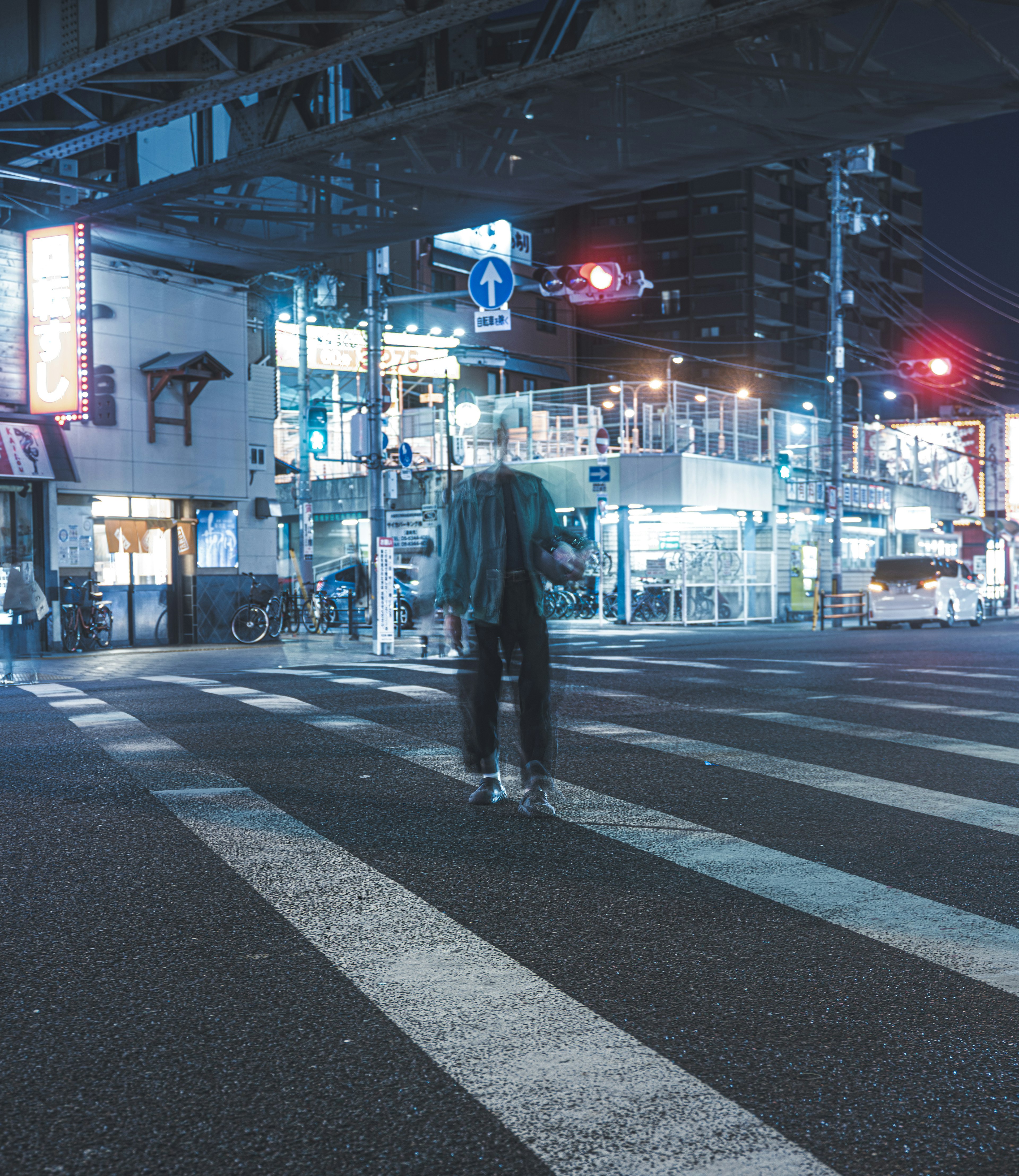 夜の交差点で立つ人物と周囲の明るい看板