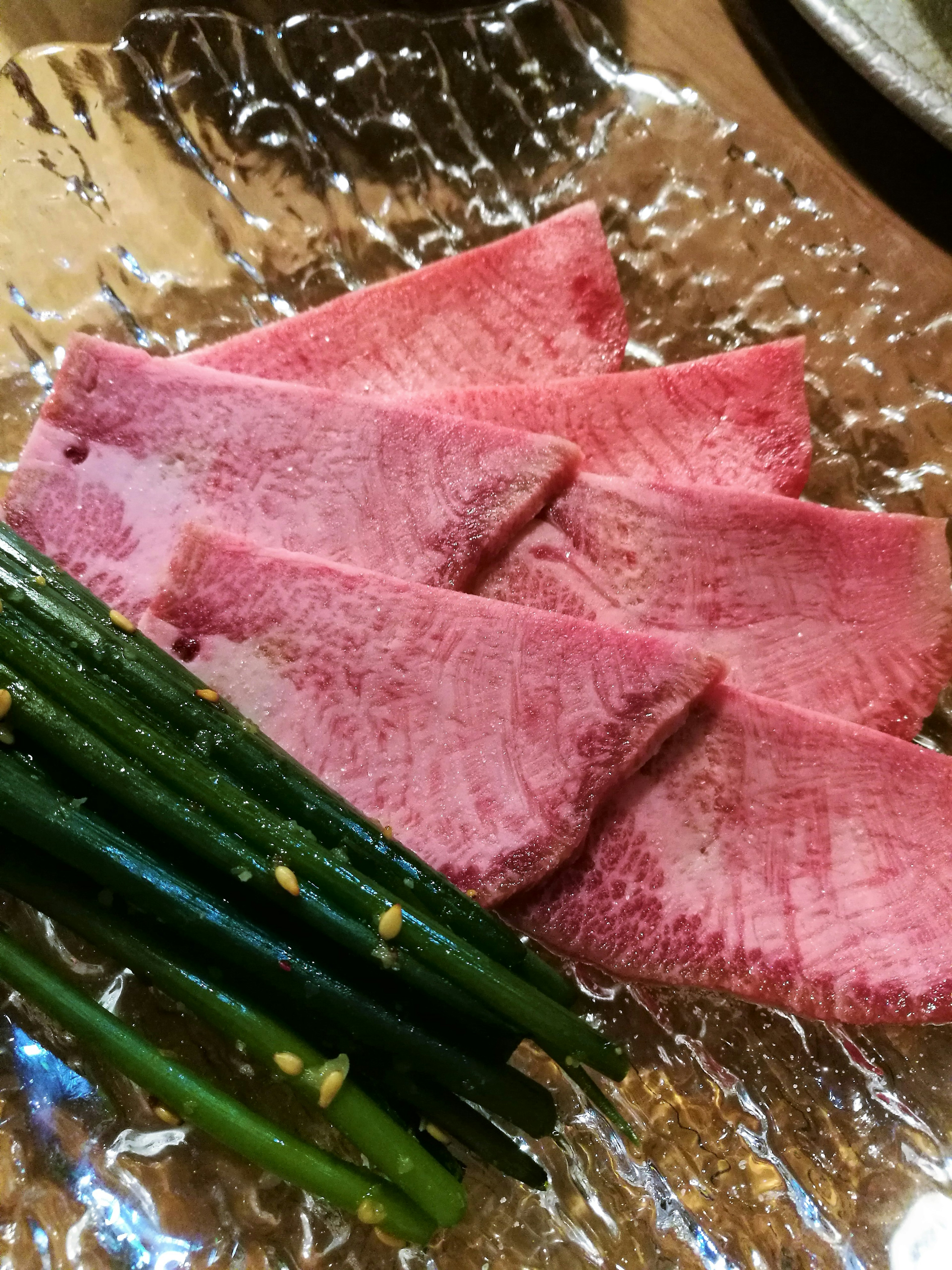 Schön angeordnete Scheiben von Wagyu-Rindfleisch mit gegrillten Frühlingszwiebeln