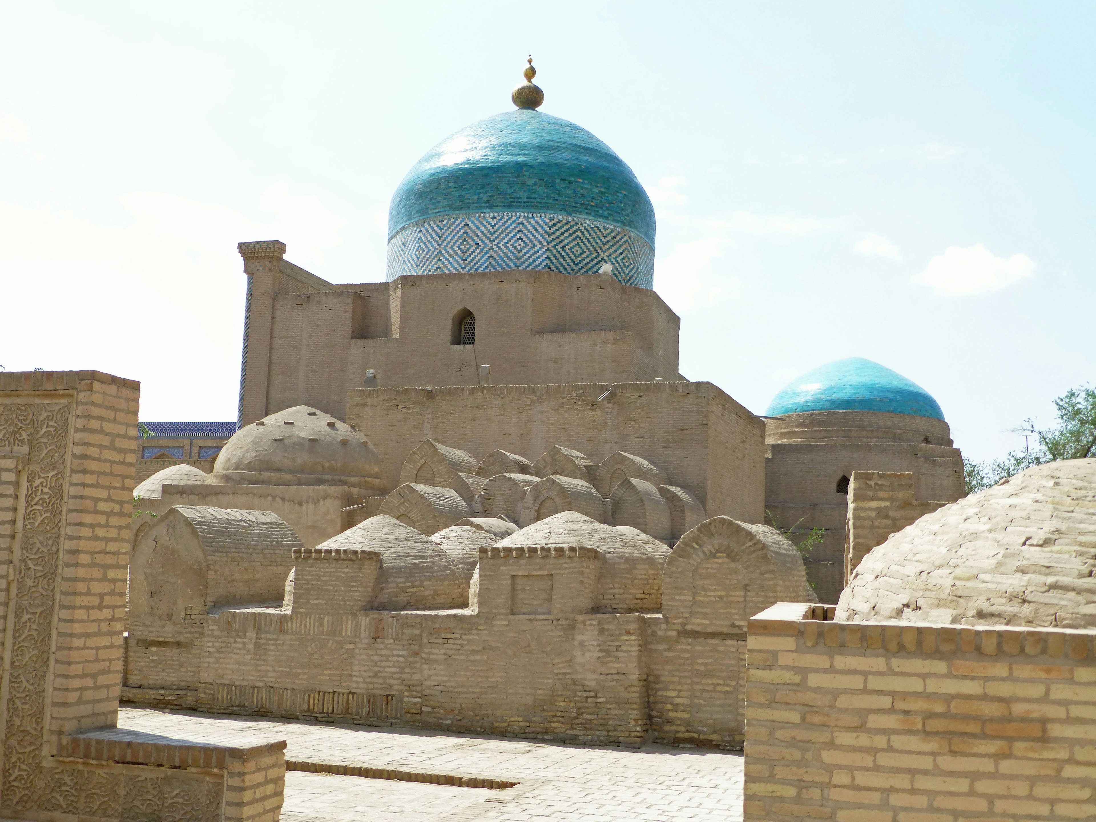 Side view of a historic building with blue domes and surrounding earthen walls