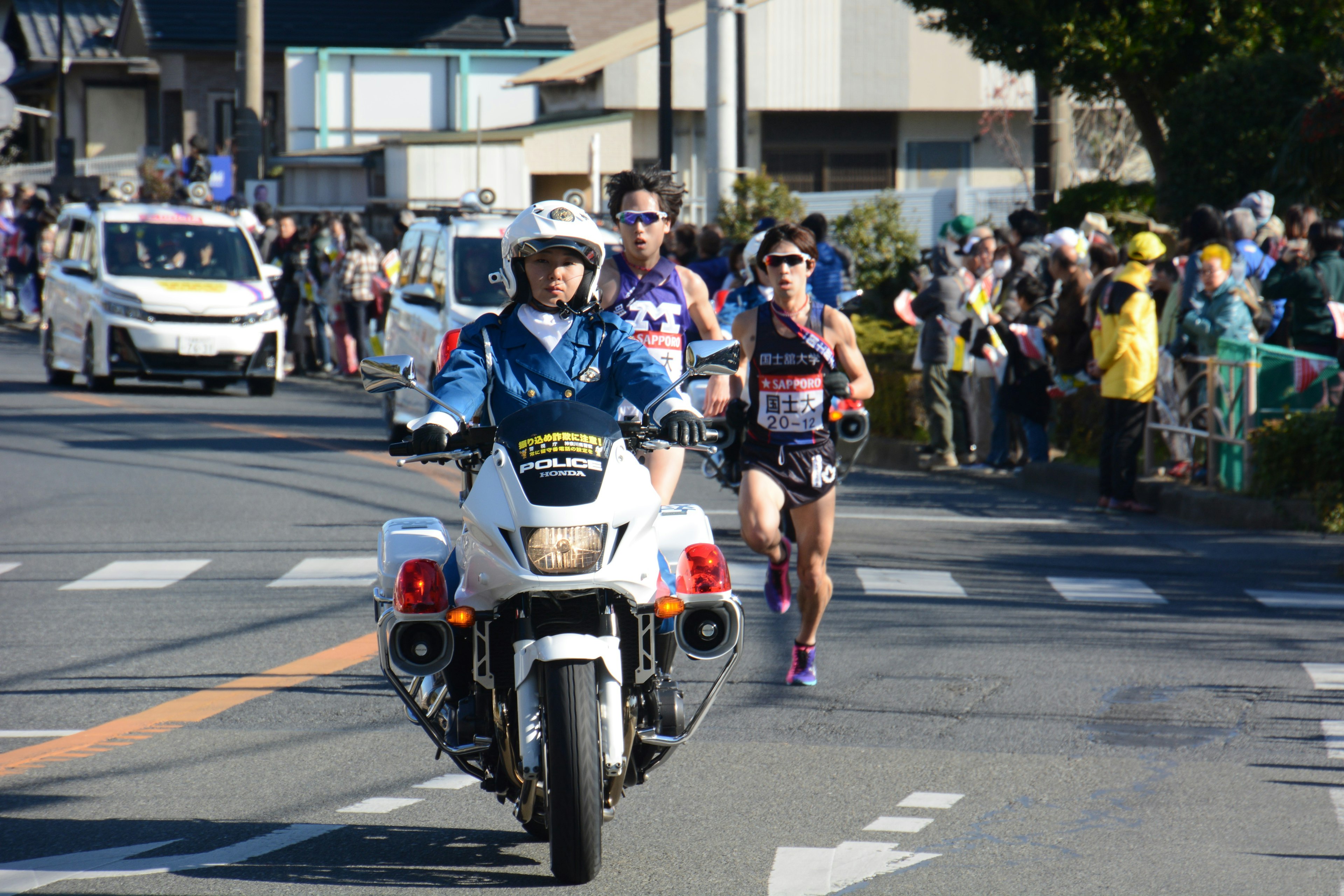 ランニングイベントの選手たちとパトカーが並ぶ風景