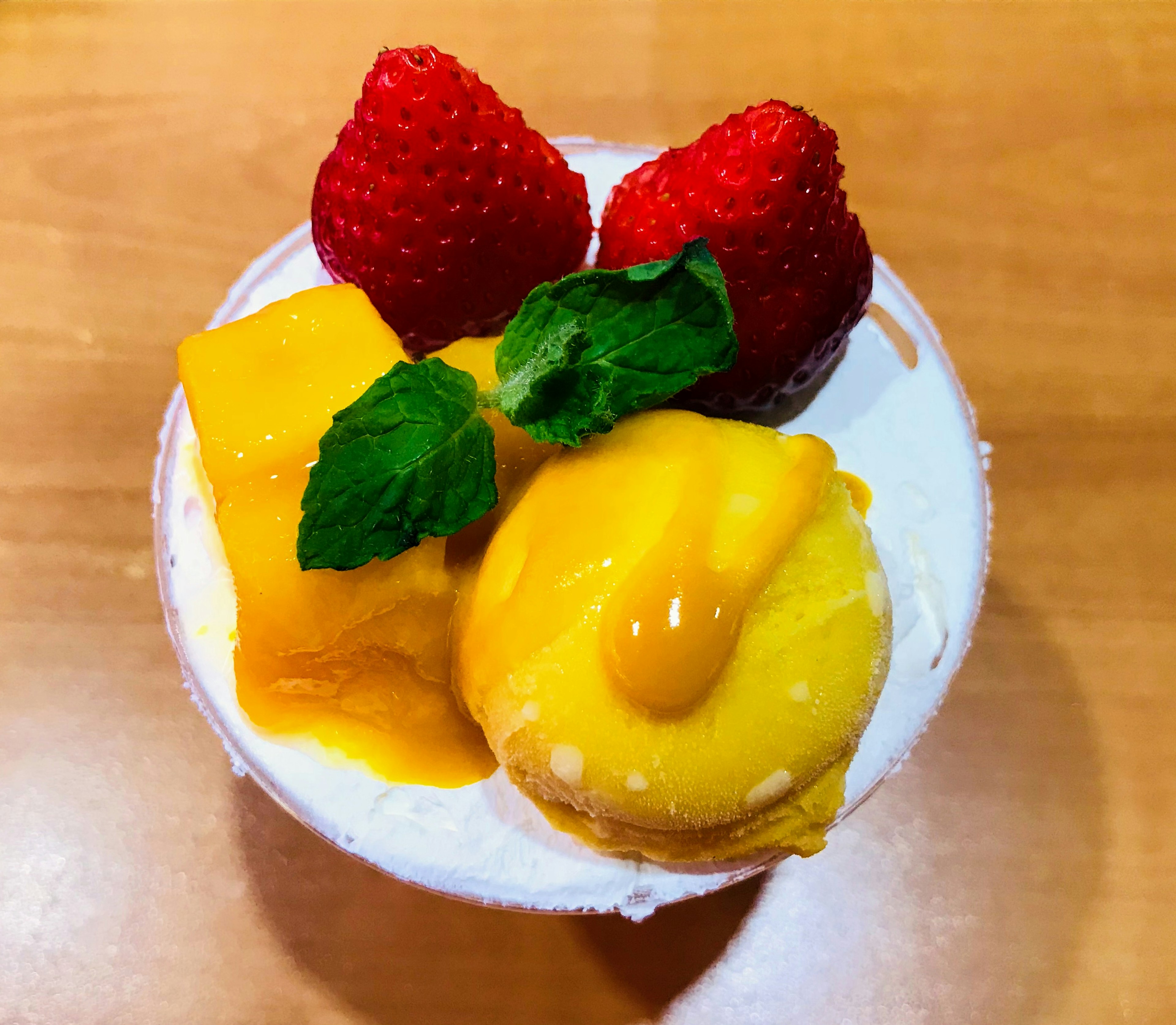 Dessert avec mangue, fraises et menthe sur de la crème fouettée