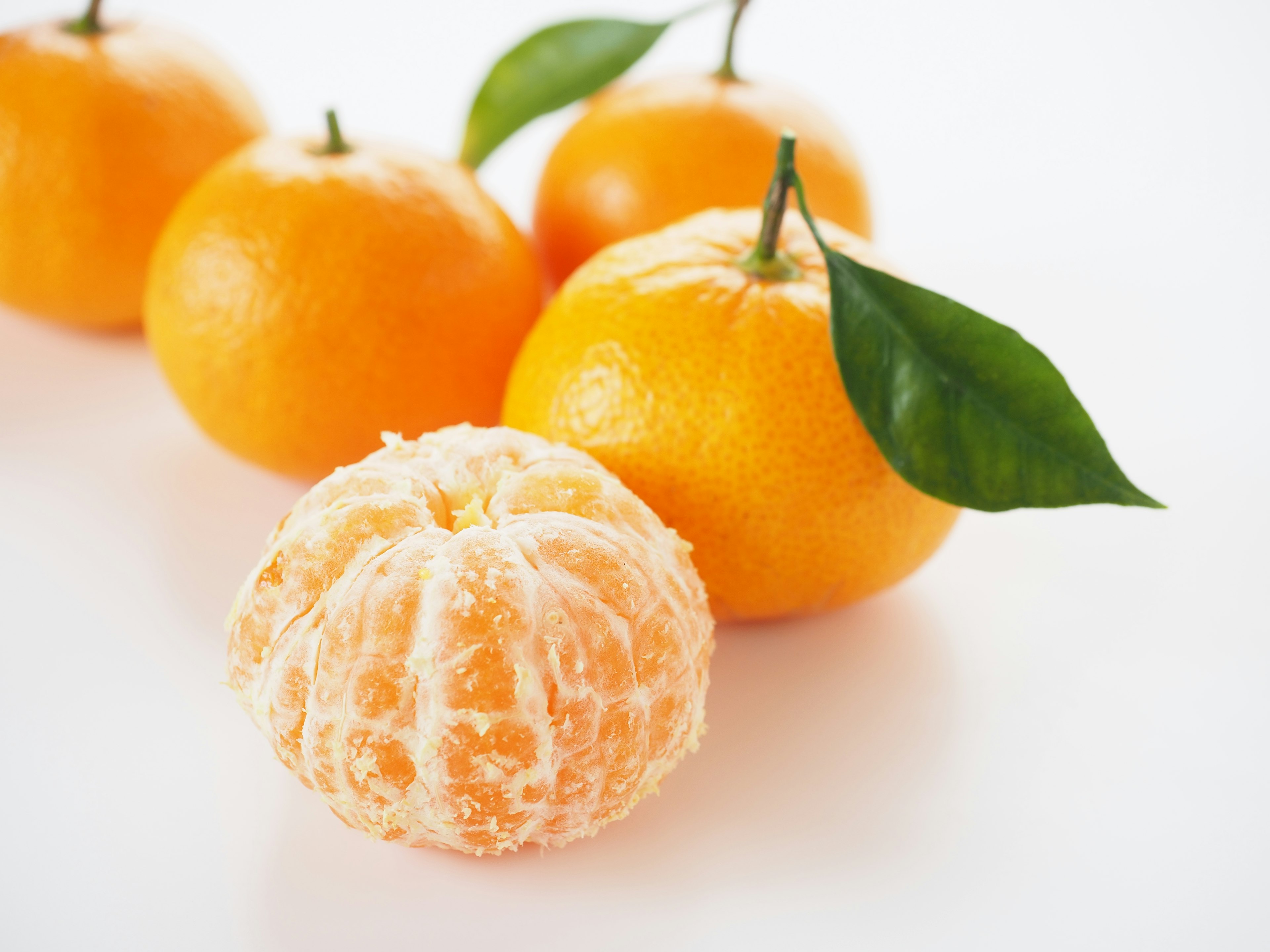 Imagen de mandarinas naranjas dispuestas con una mandarina pelada en primer plano