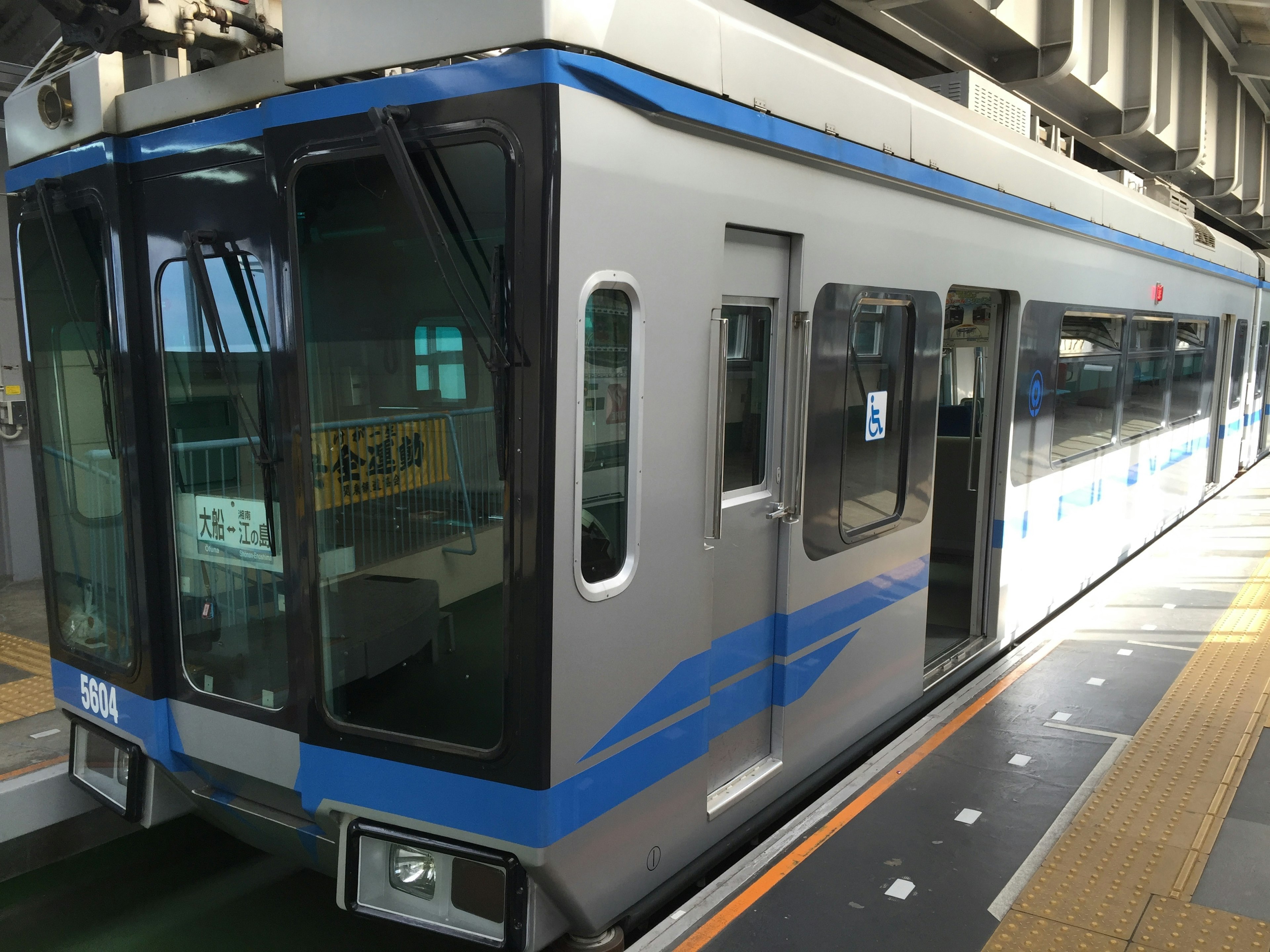 Silver train with blue stripes parked at a station