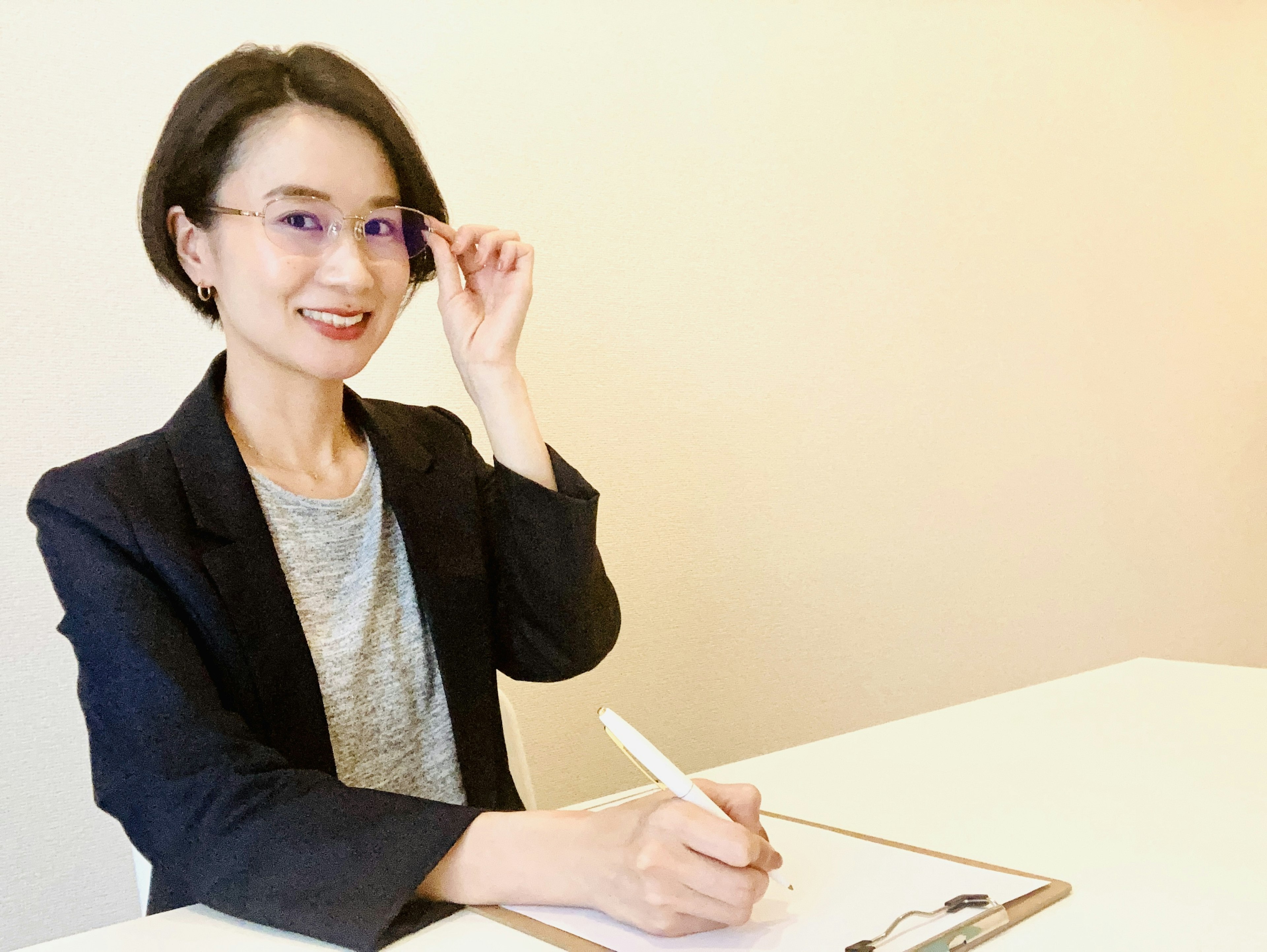 Smiling woman wearing glasses holding a pen in an office setting