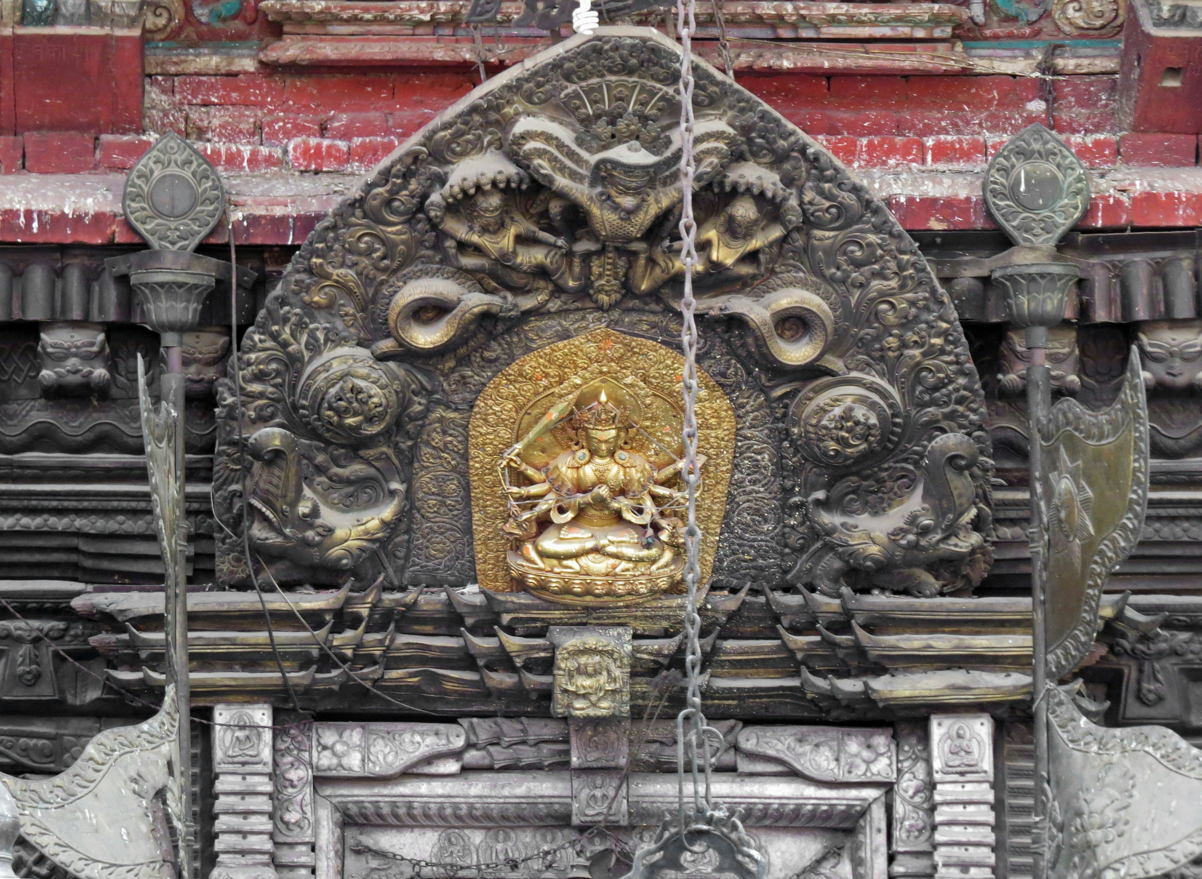 Estatua dorada de una deidad con intrincadas tallas en una decoración de templo