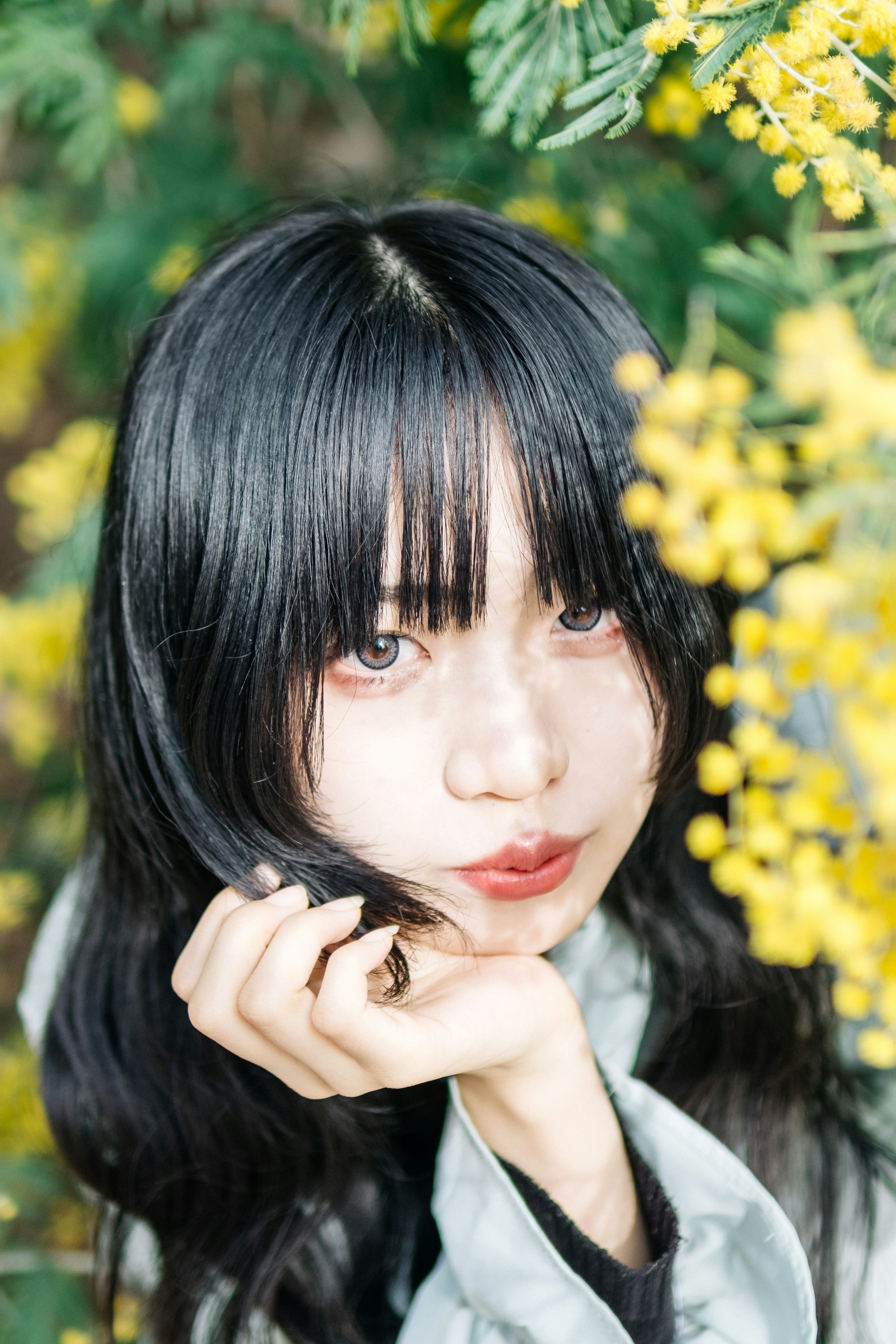 A woman posing with a smile in front of yellow flowers