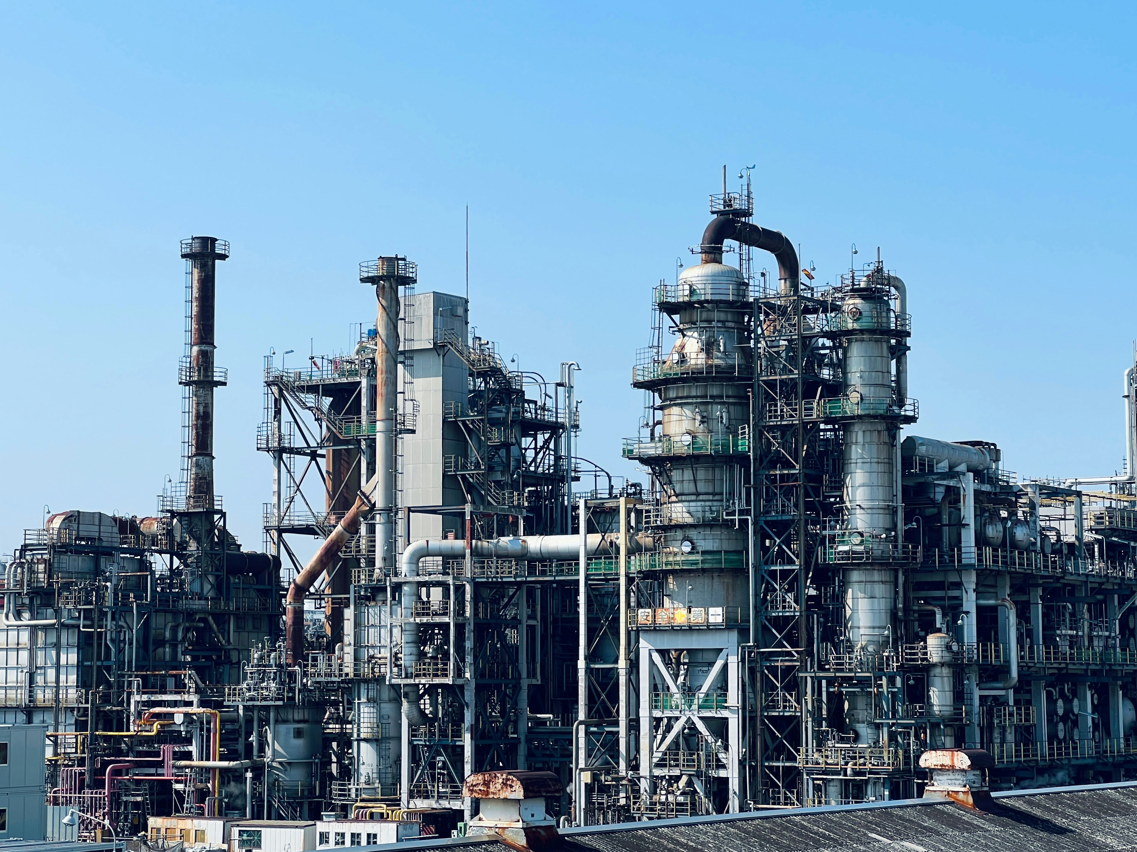 Extérieur d'une usine industrielle avec des tuyaux et des réservoirs complexes sous un ciel bleu clair