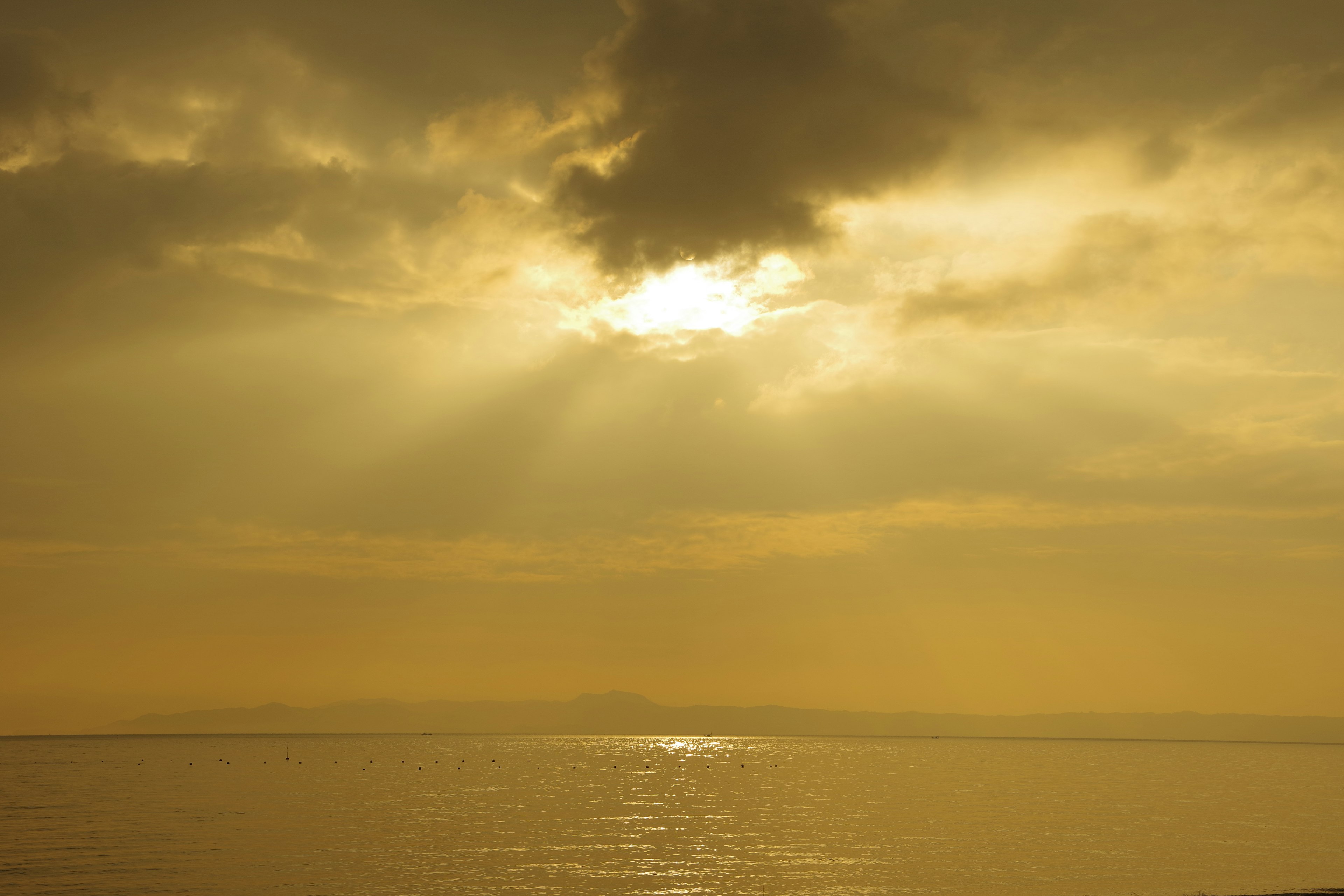 Paesaggio dorato del cielo e del mare con raggi di luce che filtrano tra le nuvole