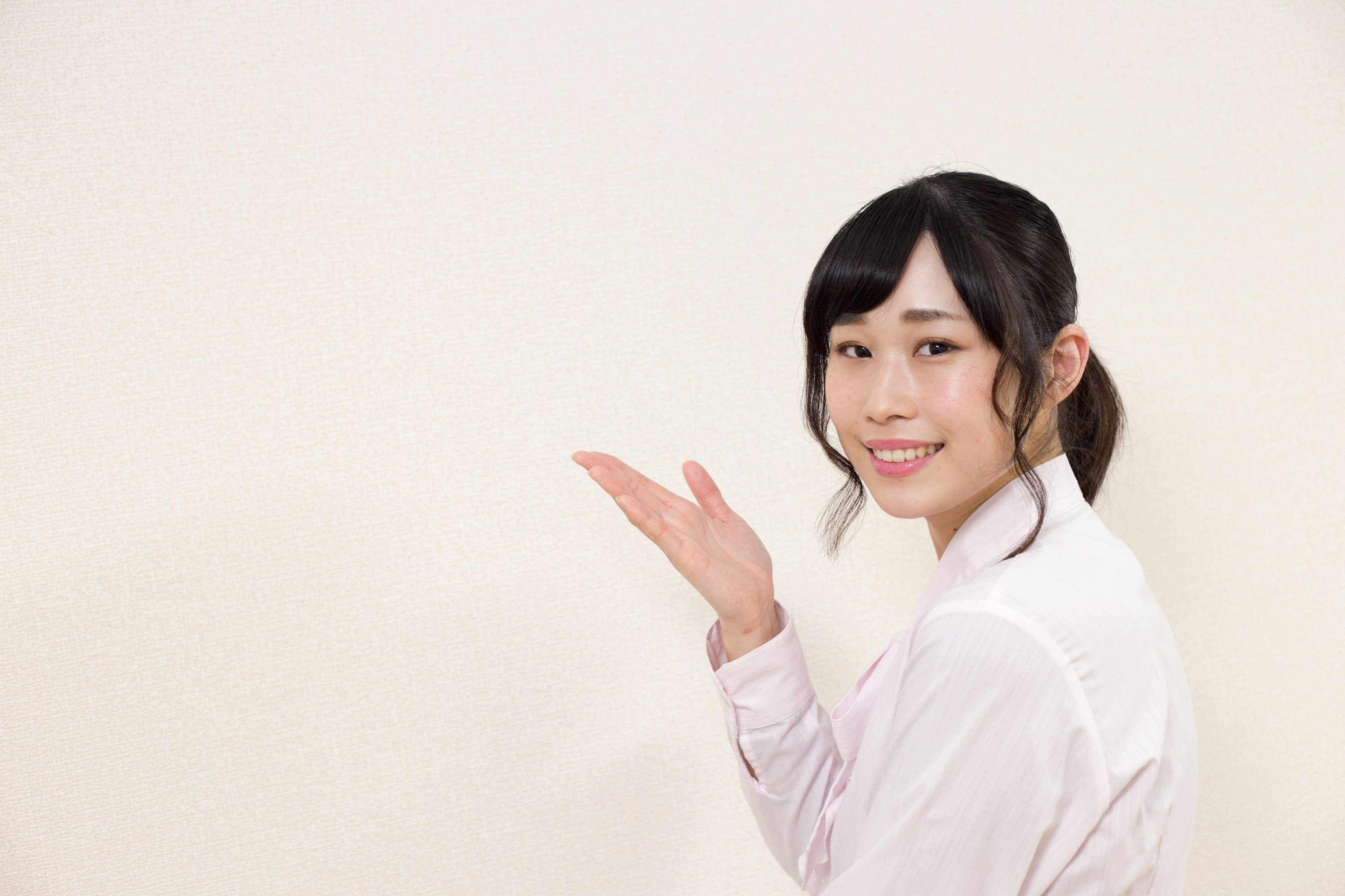 Une femme souriante tendant la main devant un fond blanc