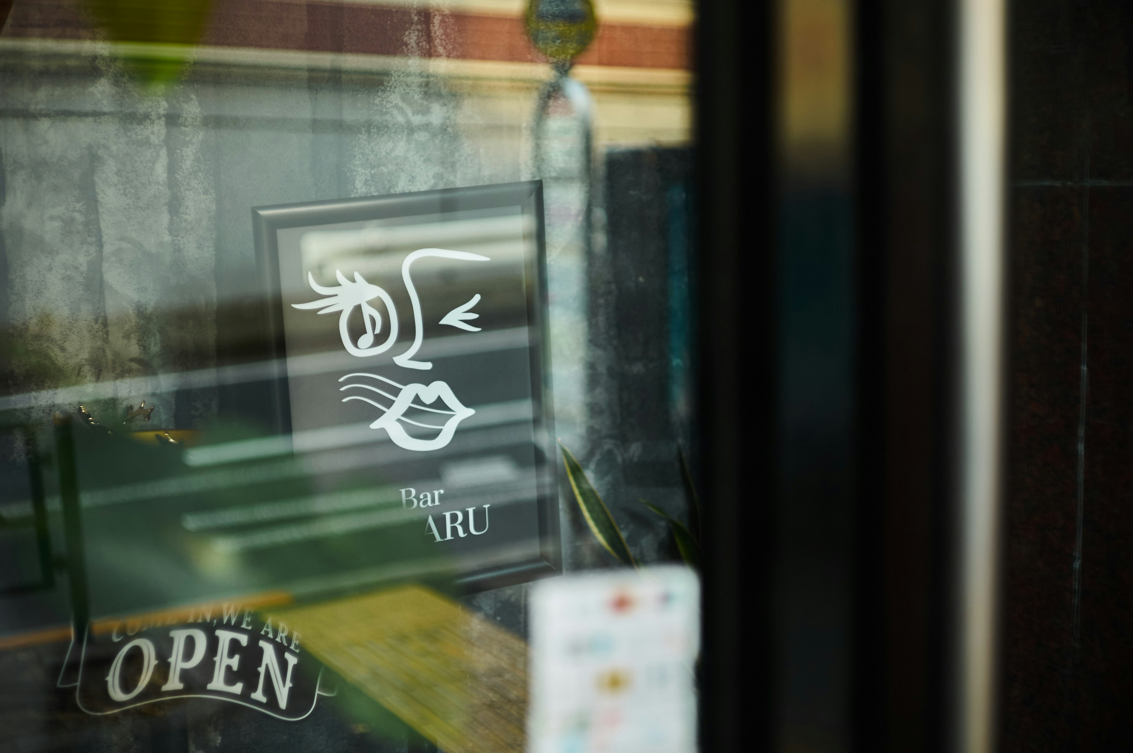 Artistic logo and open sign reflected in the window