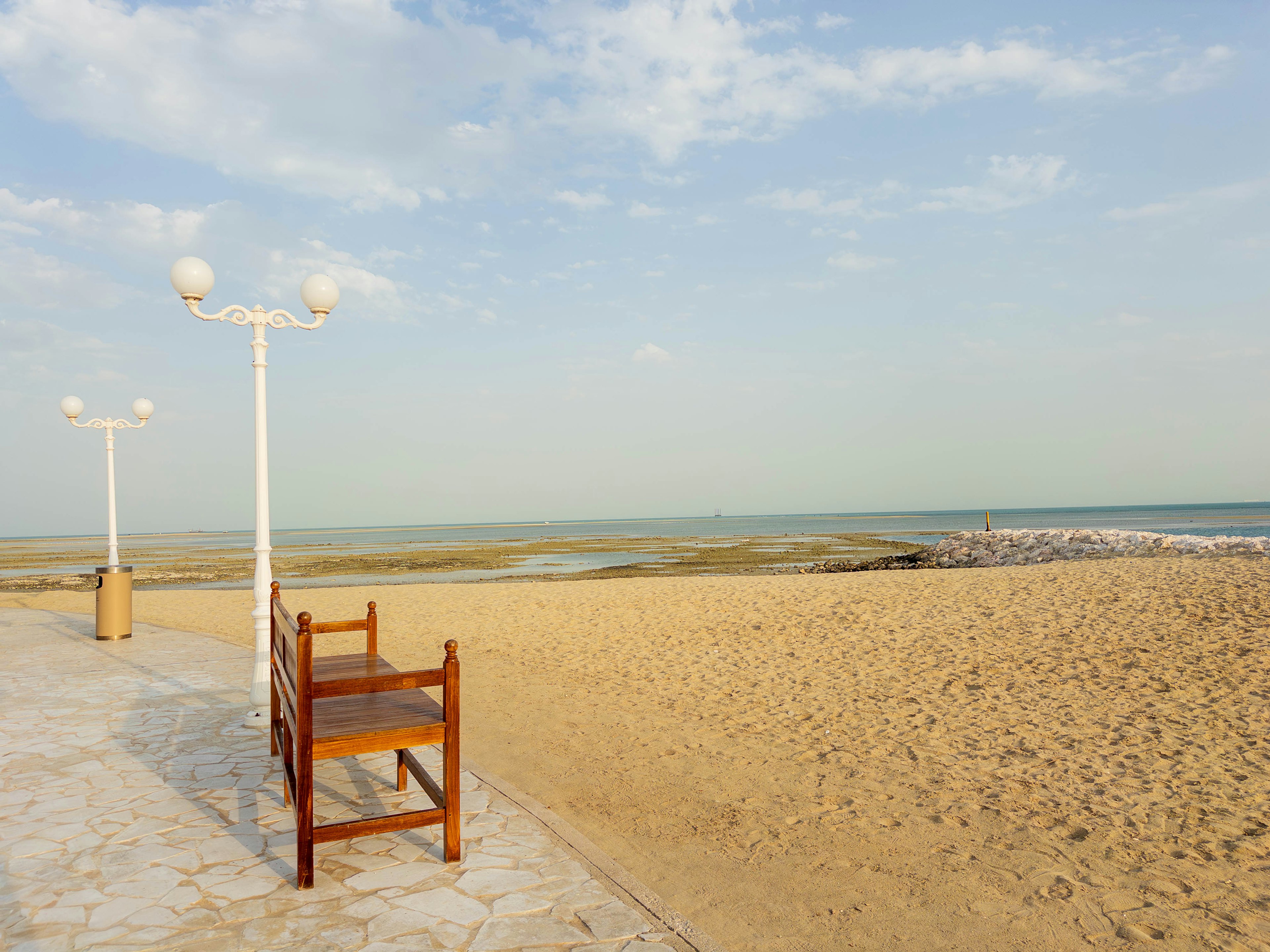 Wooden chair and streetlights on a beach scene