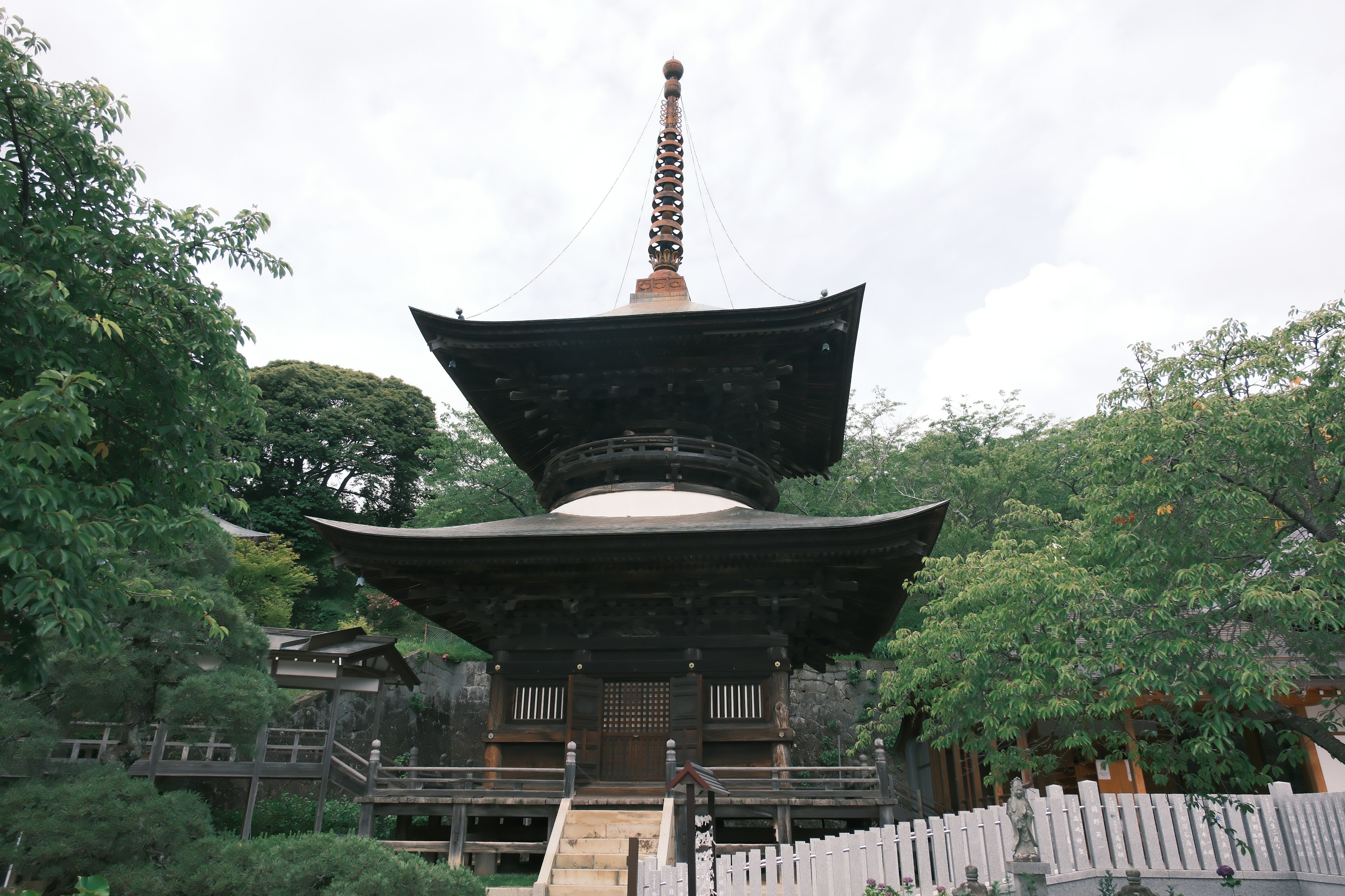 Five-story pagoda with a black roof surrounded by green trees