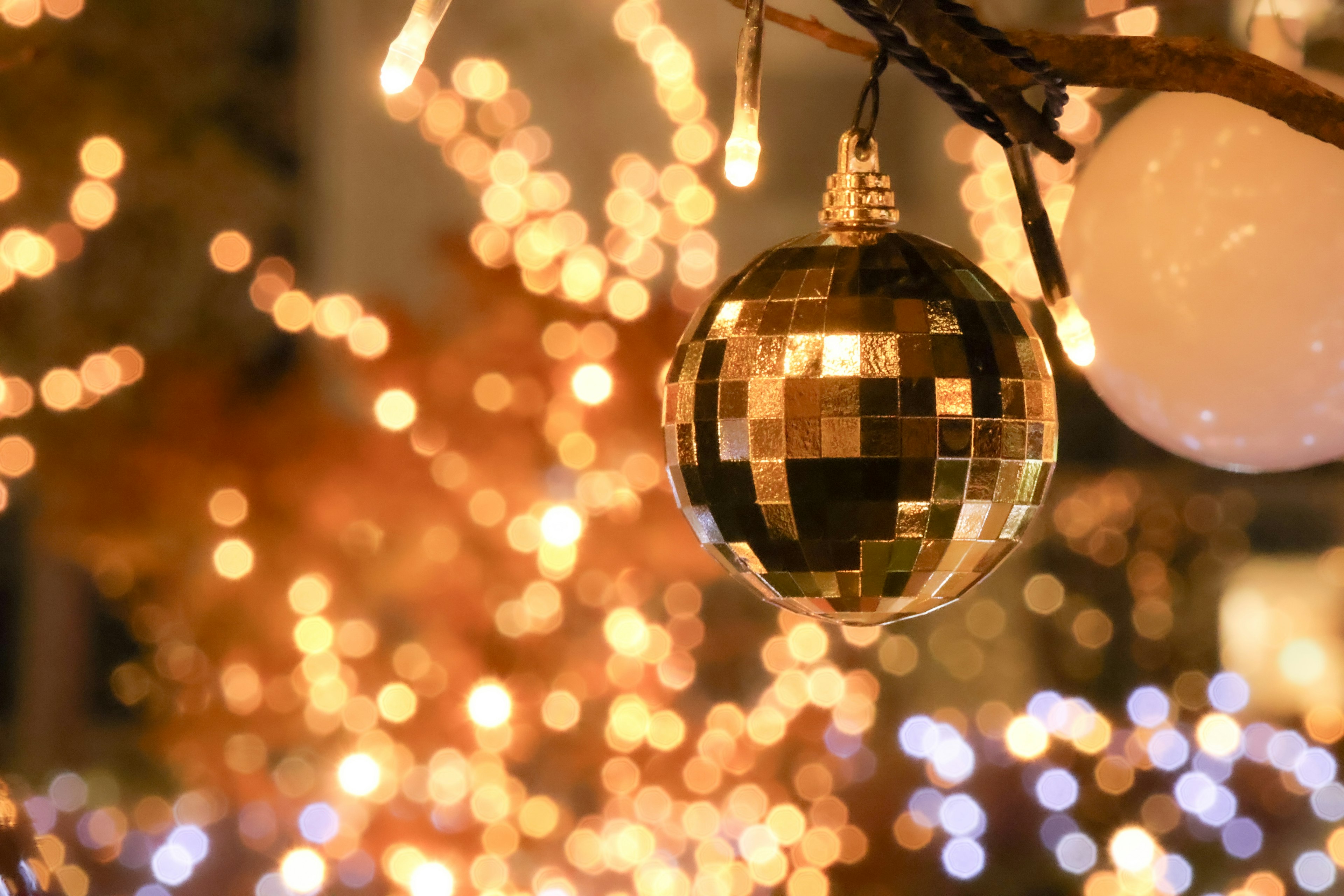 A mirror ball hanging as a Christmas decoration with a vibrant background of lights