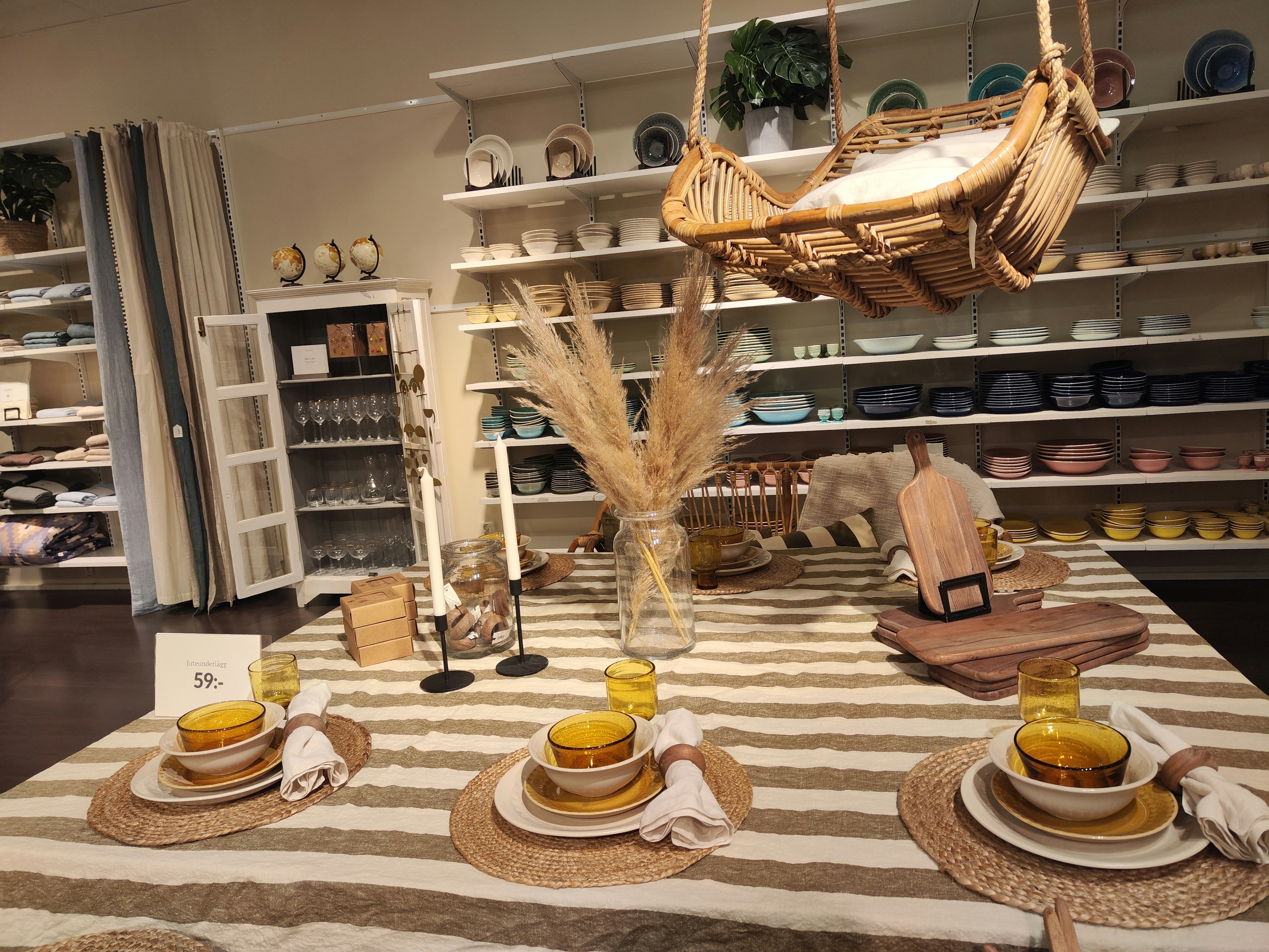 Interior design scene featuring a table setting with striped tablecloth tableware and decorative items