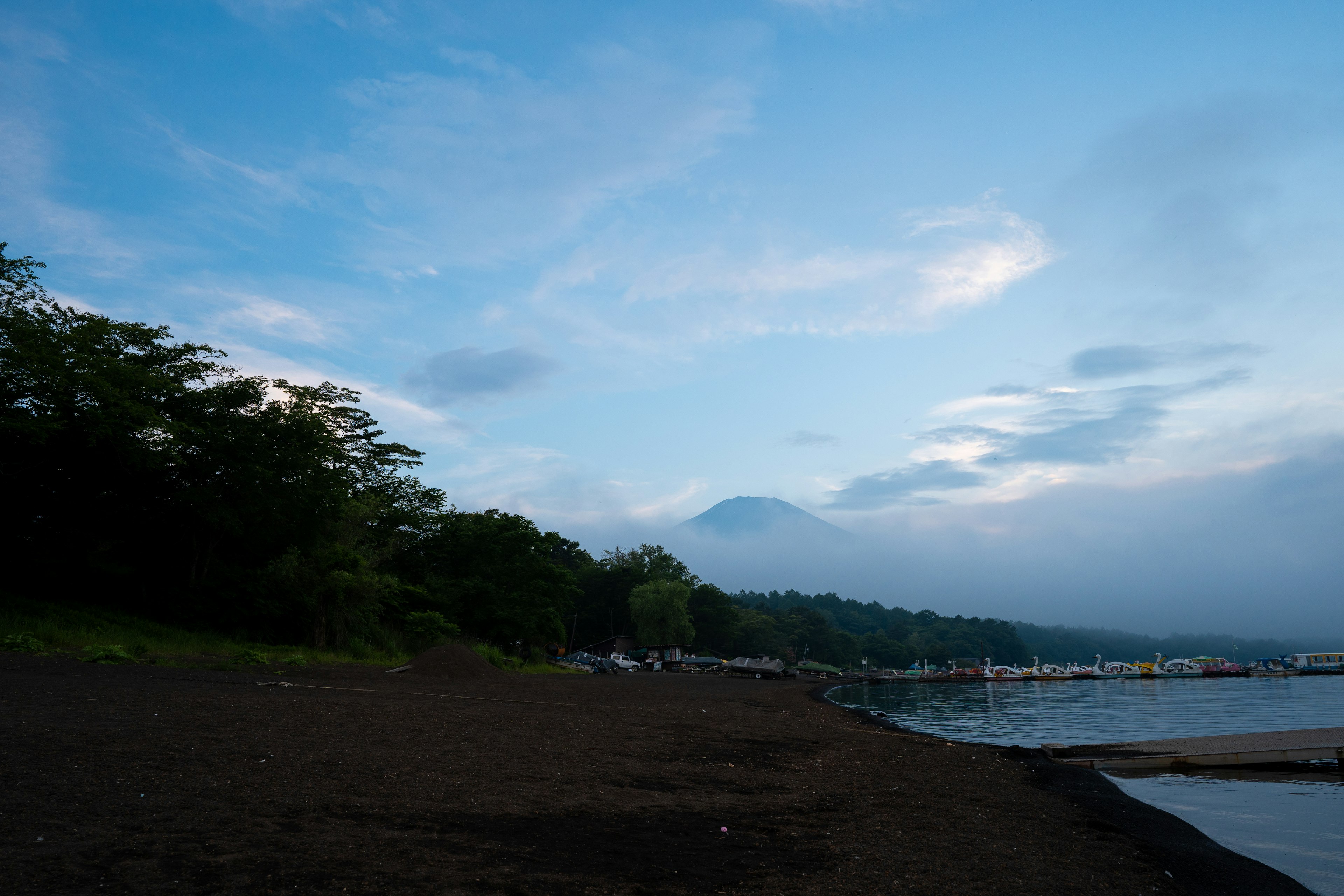 Serene lakeshore with blue sky and clouds alongside green trees