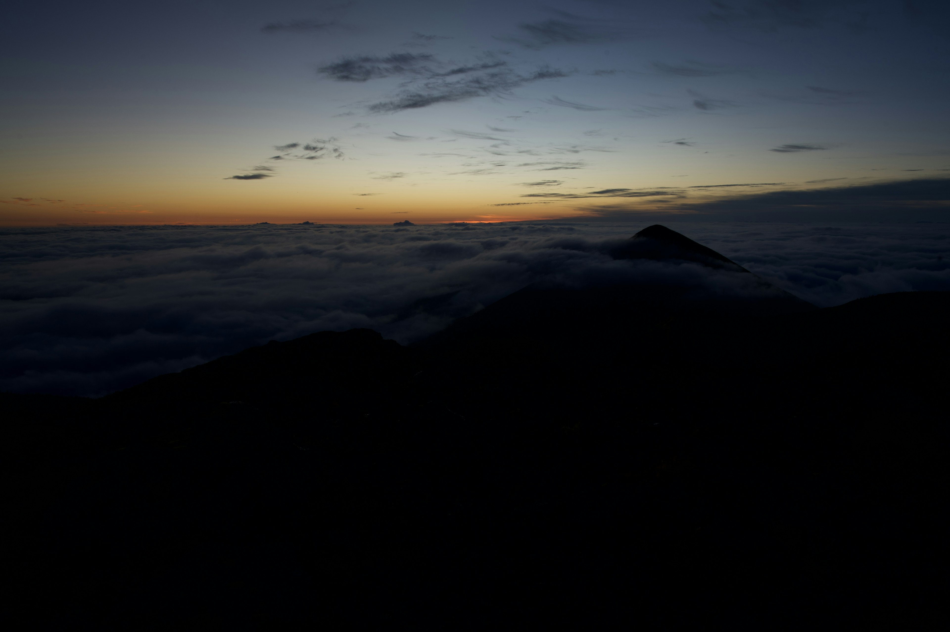 Siluet gunung saat senja dengan lautan awan