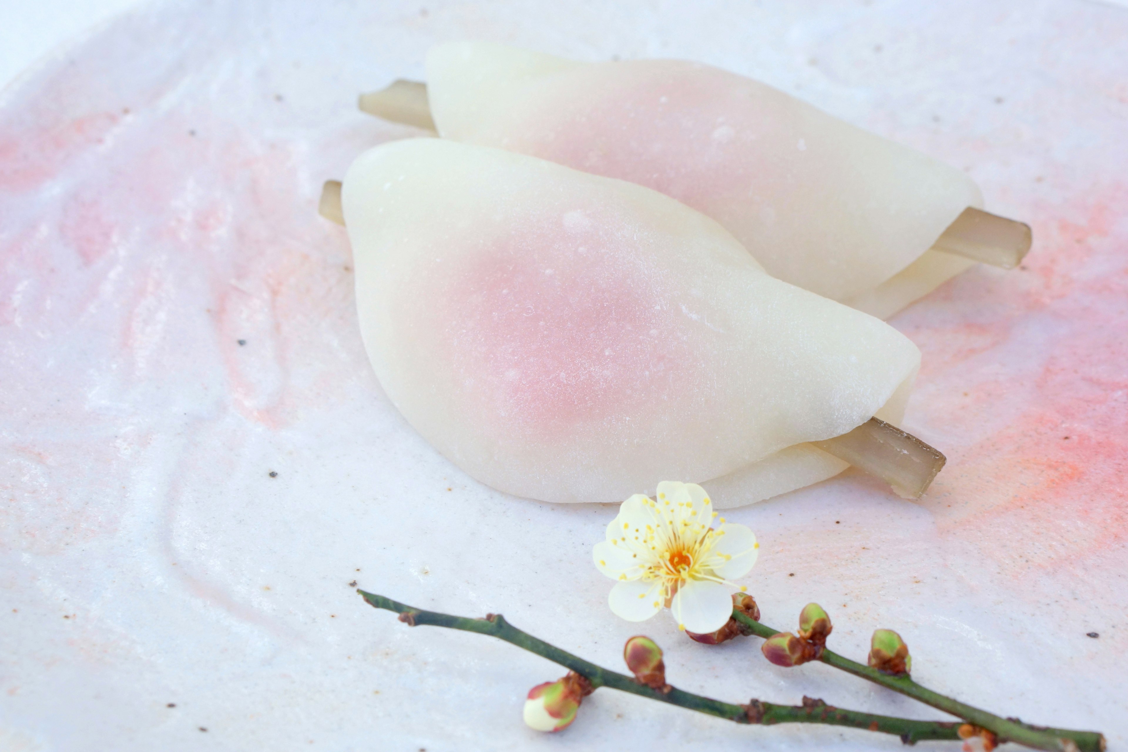 Two heart-shaped sweets with white and pink colors placed on a textured surface