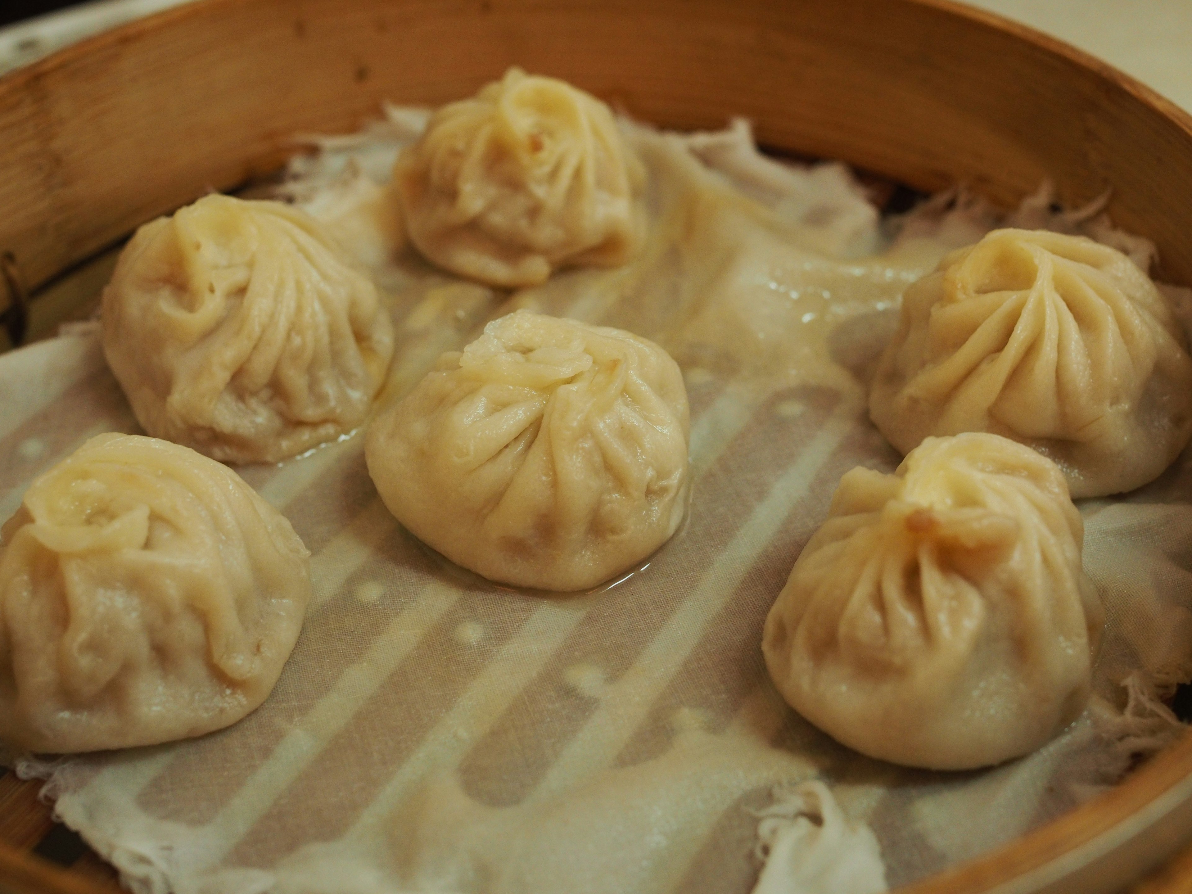 Six steamed dumplings arranged in a bamboo steamer