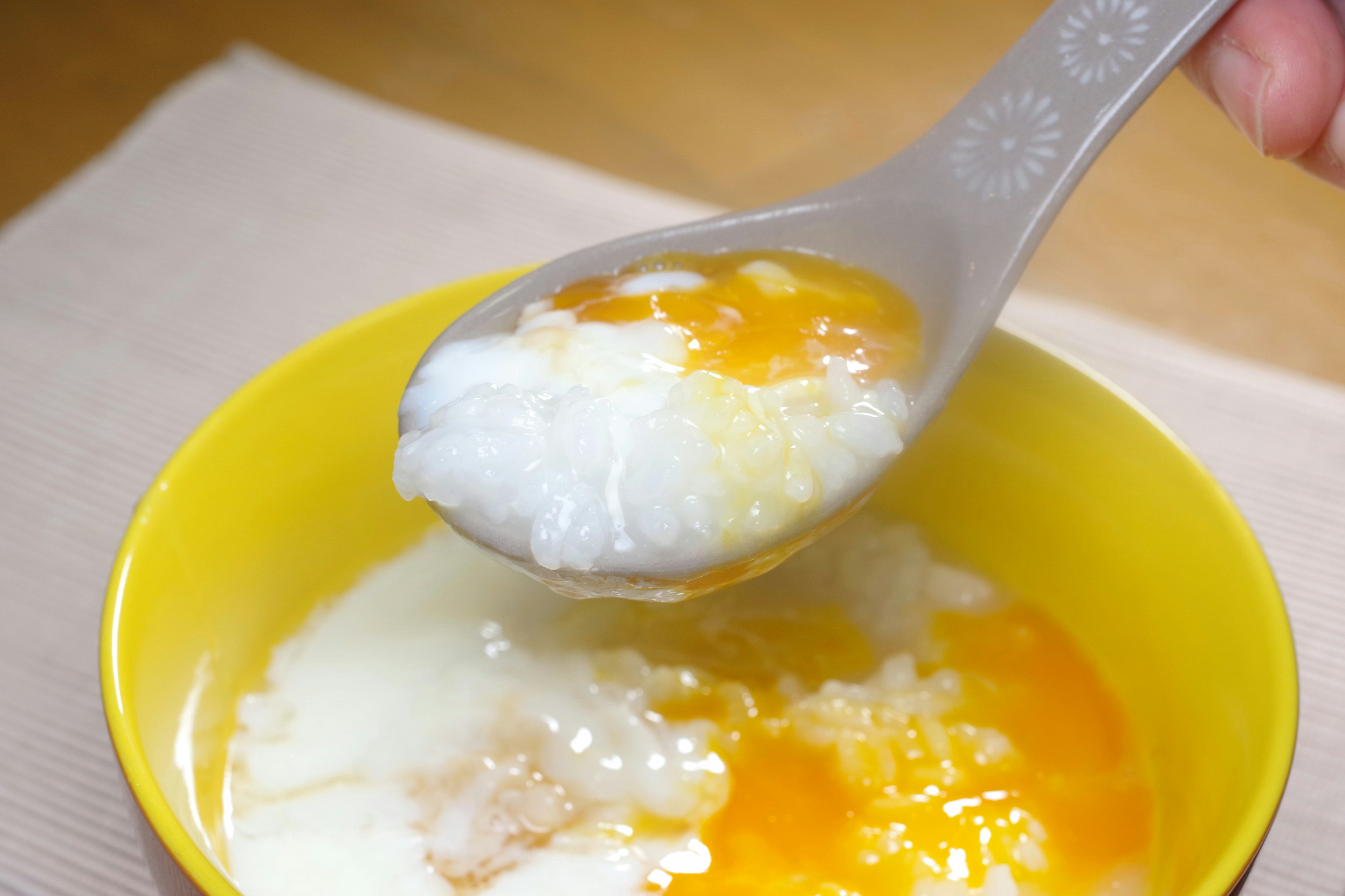 Satu sendok nasi hangat dengan kuning telur dalam mangkuk kuning