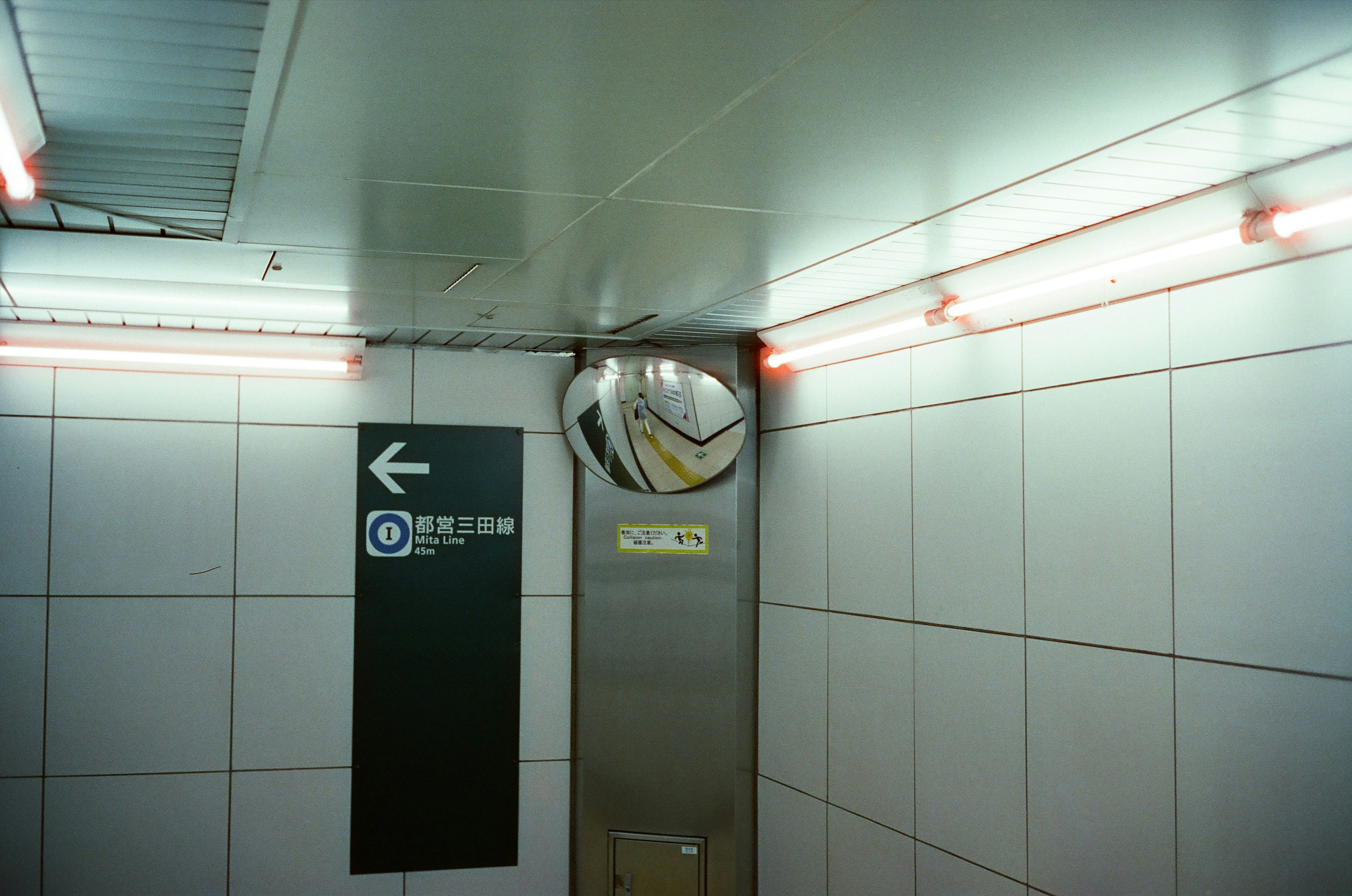 Miroir et panneau au coin d'un couloir de station de métro