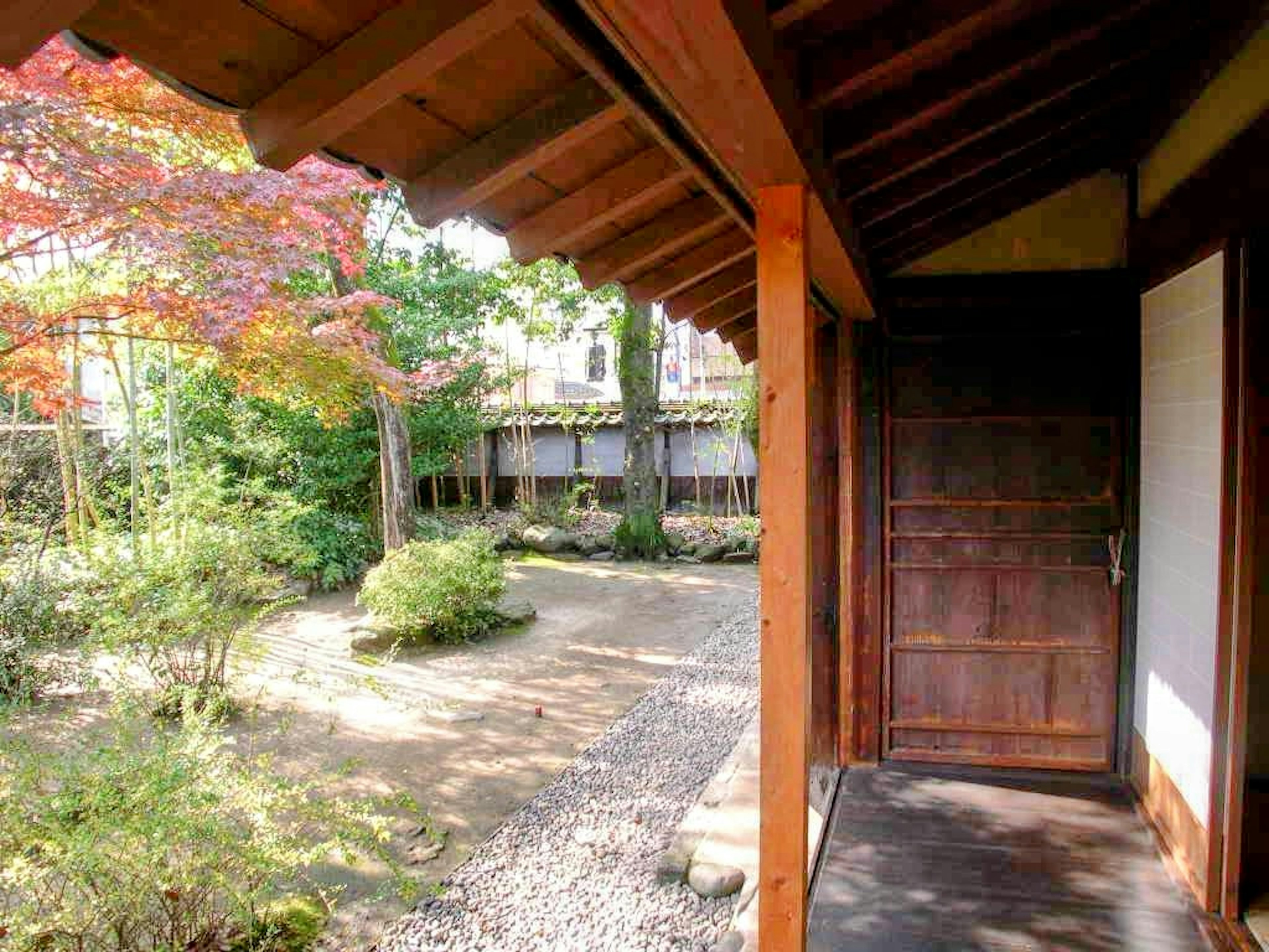 Entrance of a traditional Japanese building with a wooden door and garden view