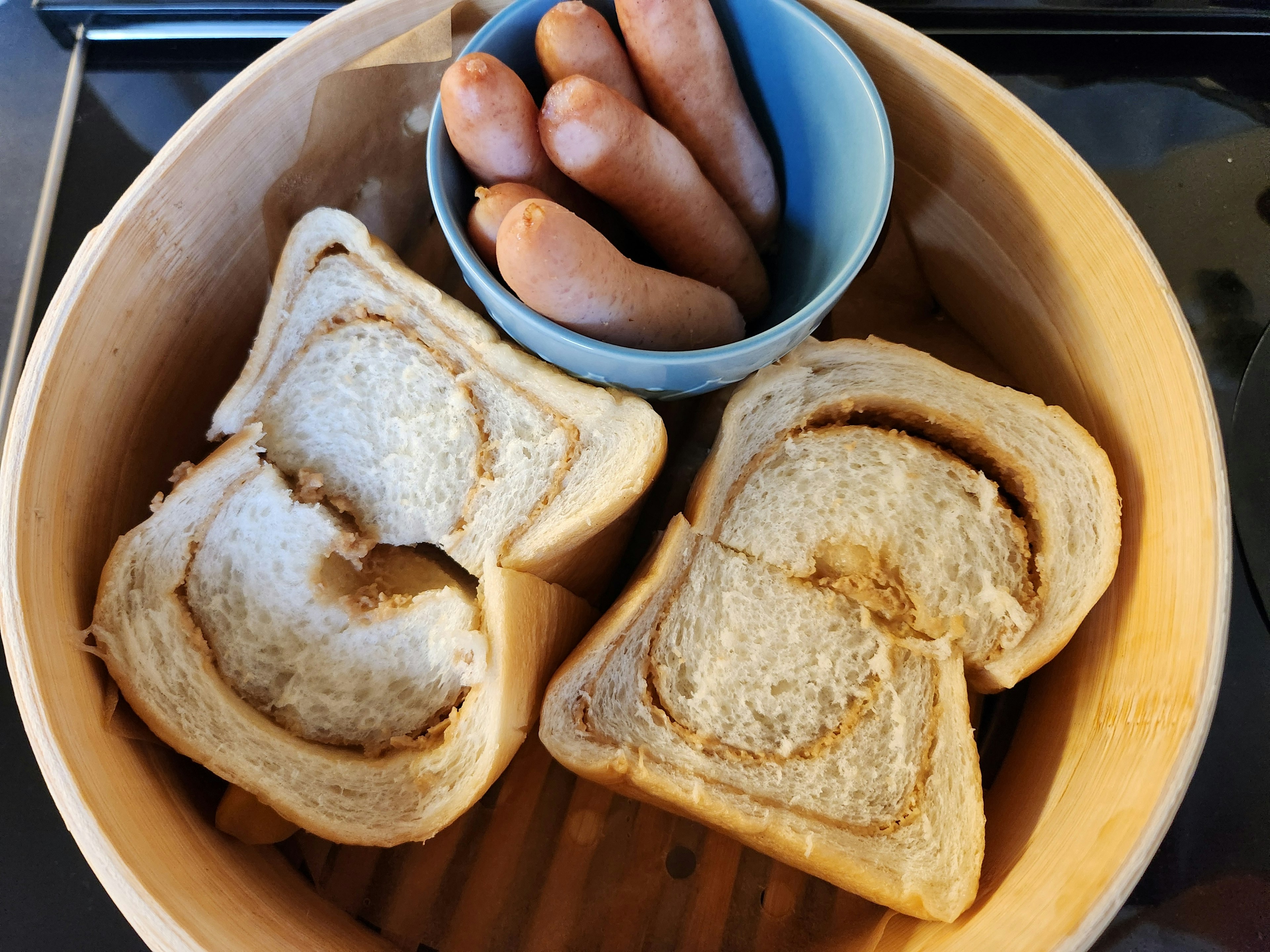 蒸し器の中にある食パンと青いボウルに入ったウィンナー