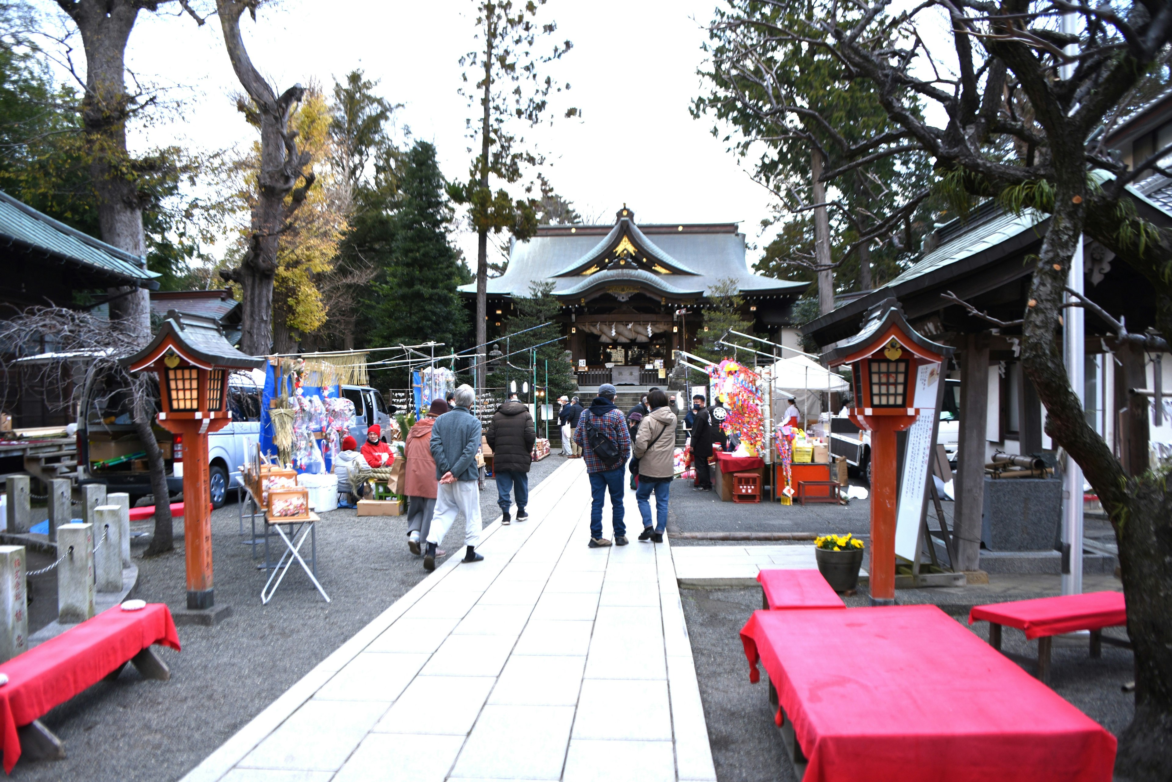 神社の参道に人々が集まる風景赤いベンチと露店が並ぶ